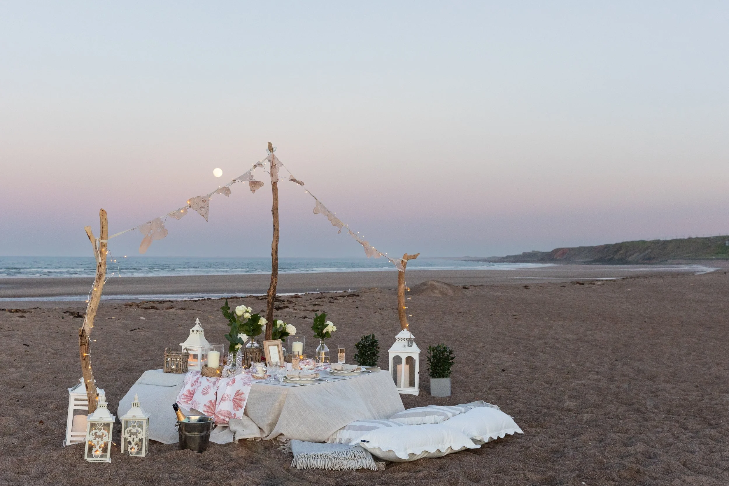 Romantic seaside proposal at Spittal Beach in Northumberland featuring bespoke styling, candlelight, seasonal florals and luxury details for intimate celebration.