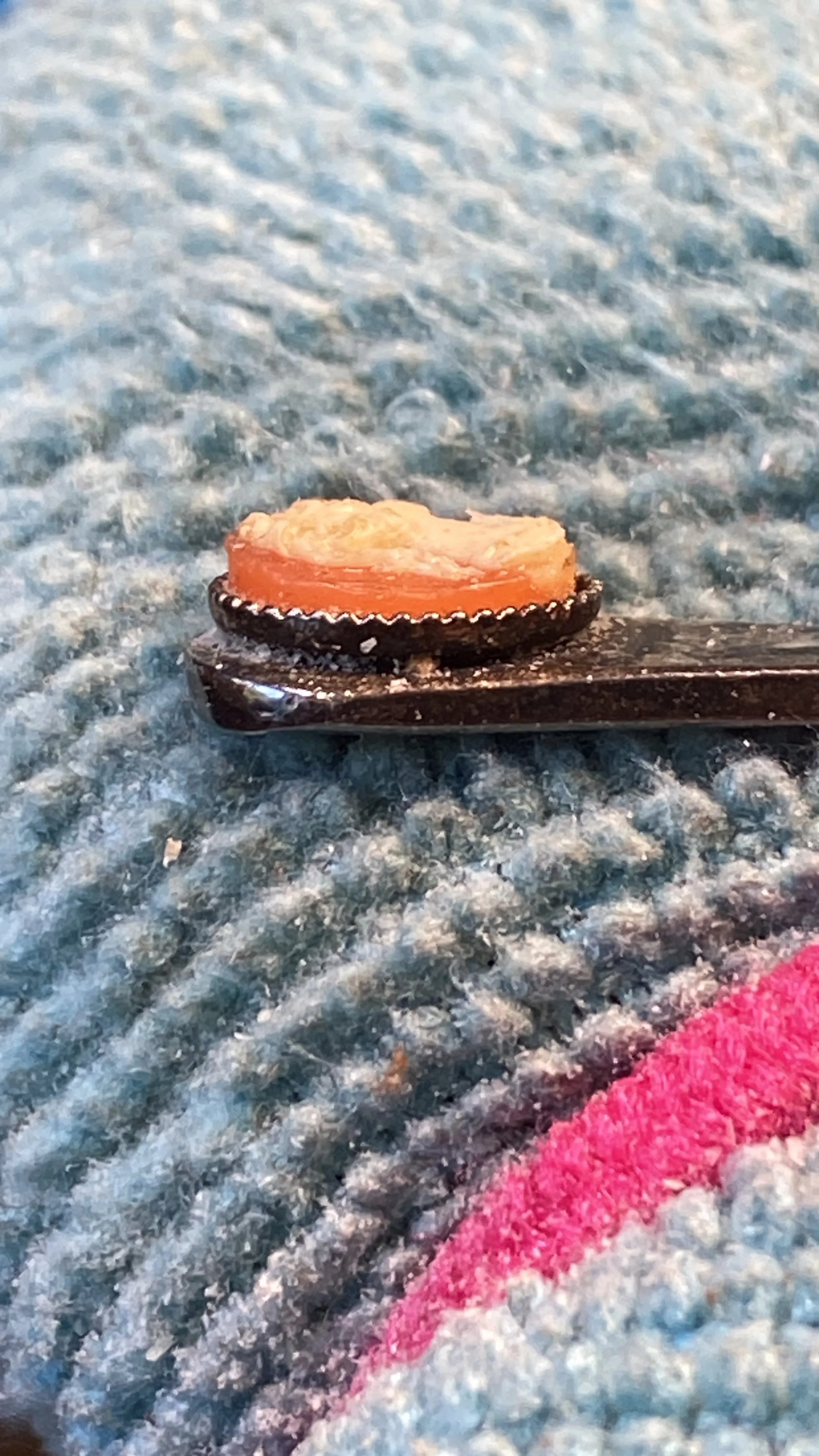 Assessing the setting, I believe this to be glued on as the setting doesn't cover the cameo. 
