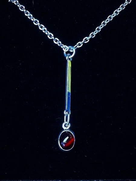 A silver necklace with a vertical pendant and a red oval gemstone pendant hanging below it.