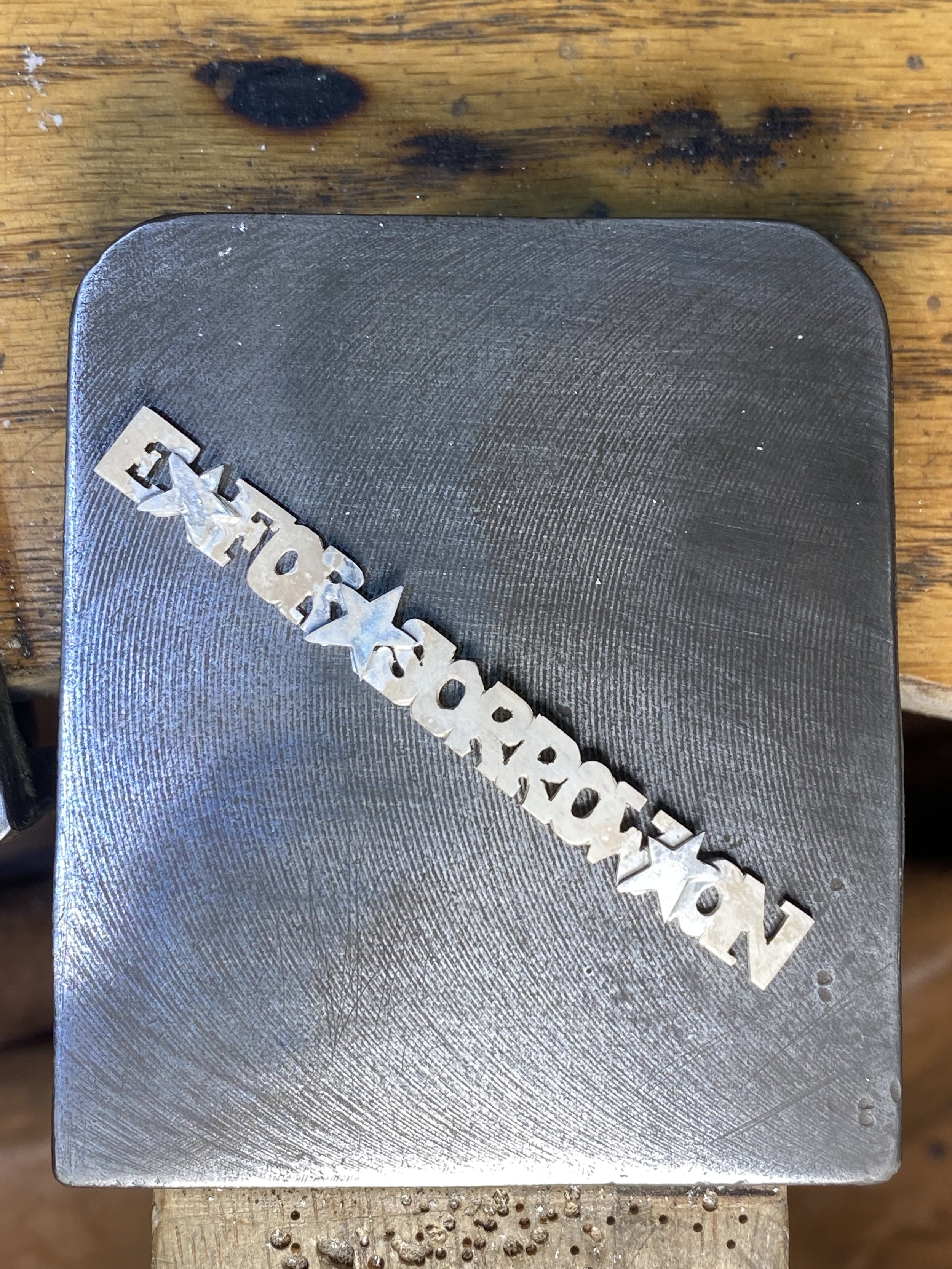 The spinner is hand cut out of sheet Silver before being soldered round and added to the centre of the ring. I added additional stars to separate the words.  