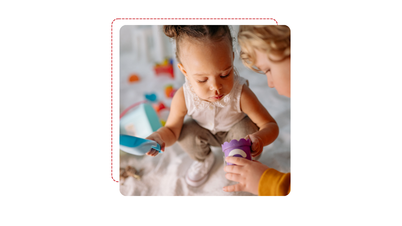 Deux jeunes enfants jouent avec des jouets dans un espace de jeux intérieur, un enfant tient un jouet violet et l'autre un jouet bleu.