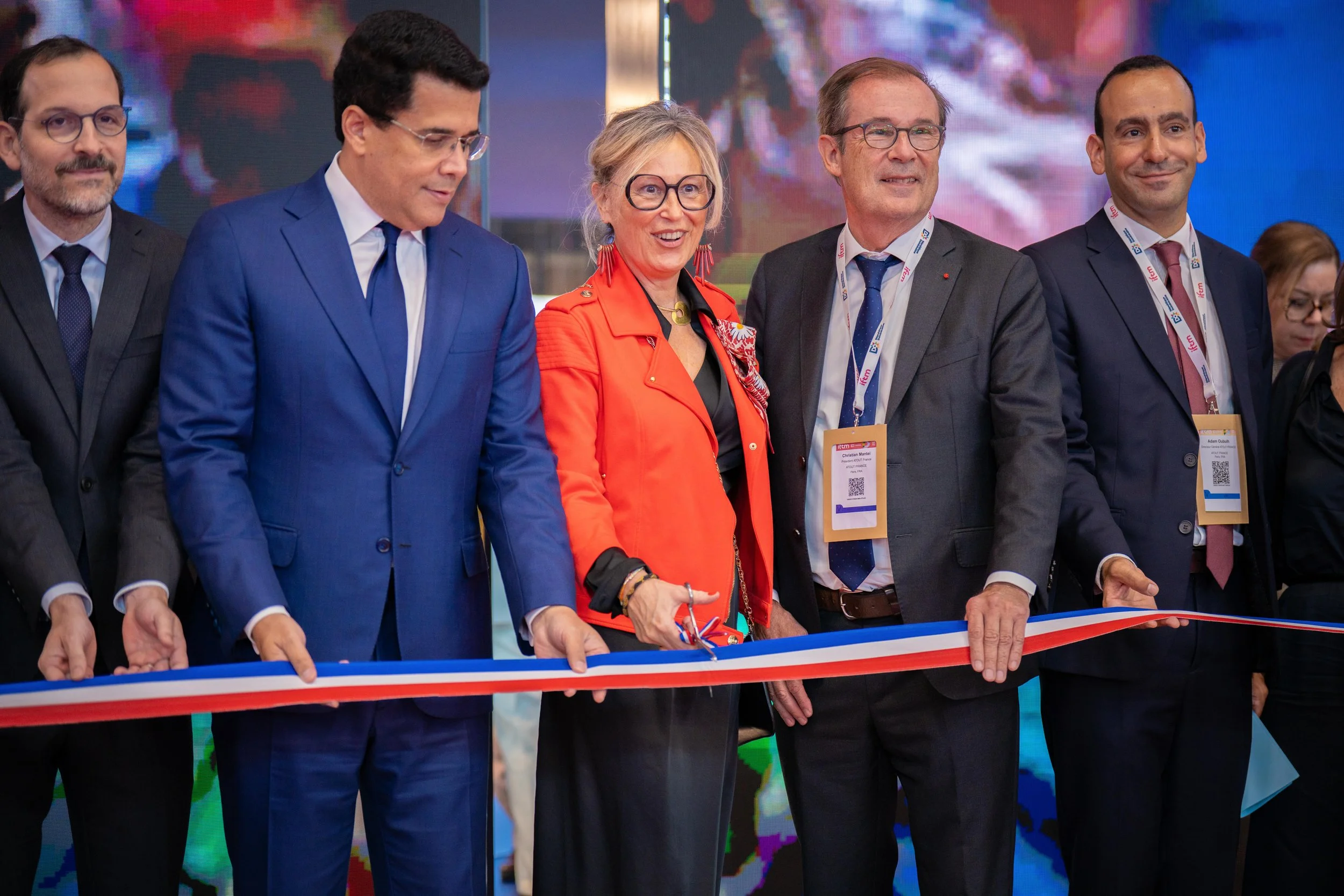 Groupe de personnes lors d'une cérémonie de découpe de ruban lors d'un événement formel.