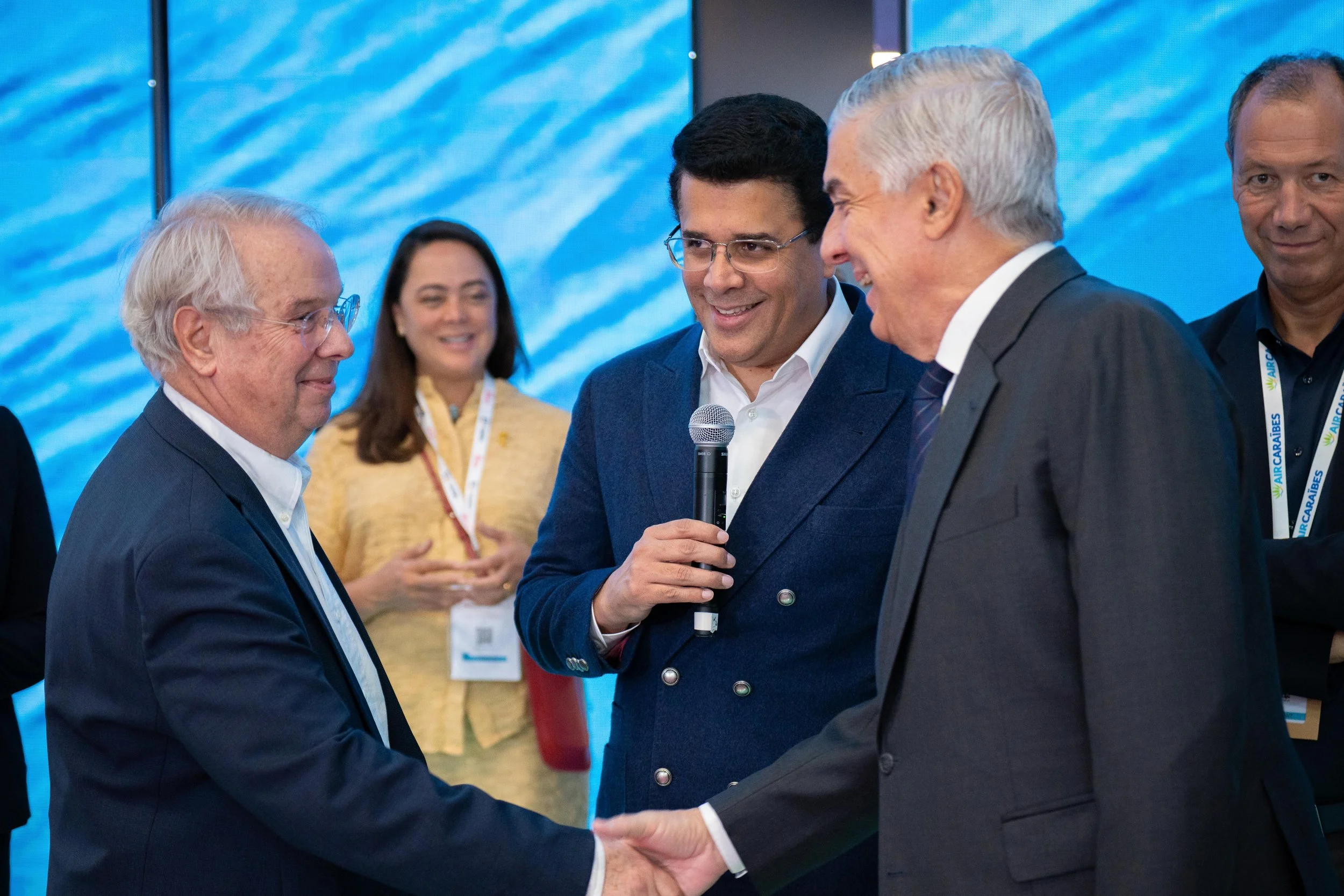 Groupe d'hommes en costume lors d'une conférence ou d'un événement professionnel, échanges et poignée de main.