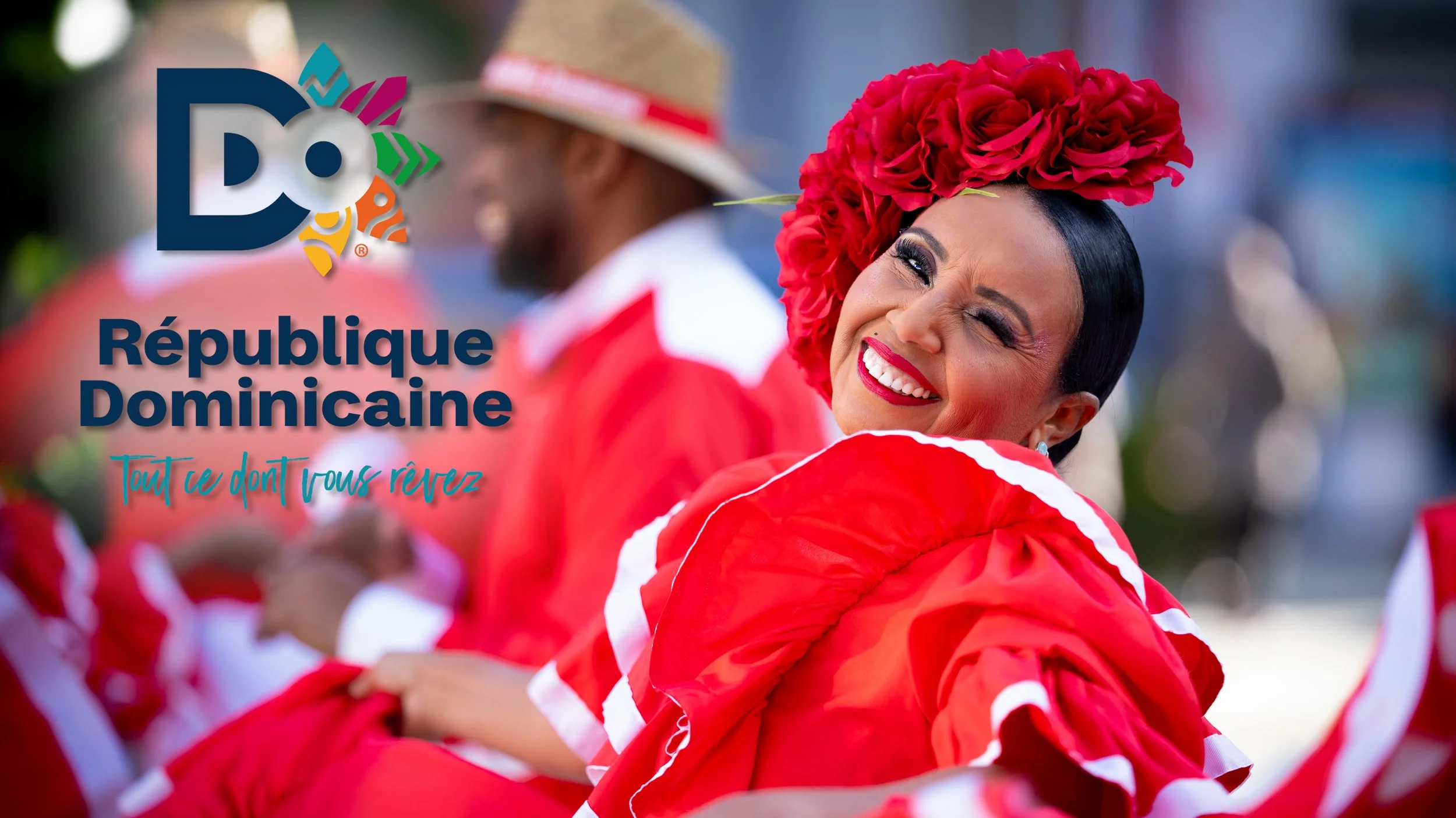 Une femme souriante portant un costume rouge avec un chapeau en roses rouges, lors d'une célébration ou parade en République Dominicaine, avec le logo de la République Dominicaine et le slogan « Tout ce dont vous rêvez ».