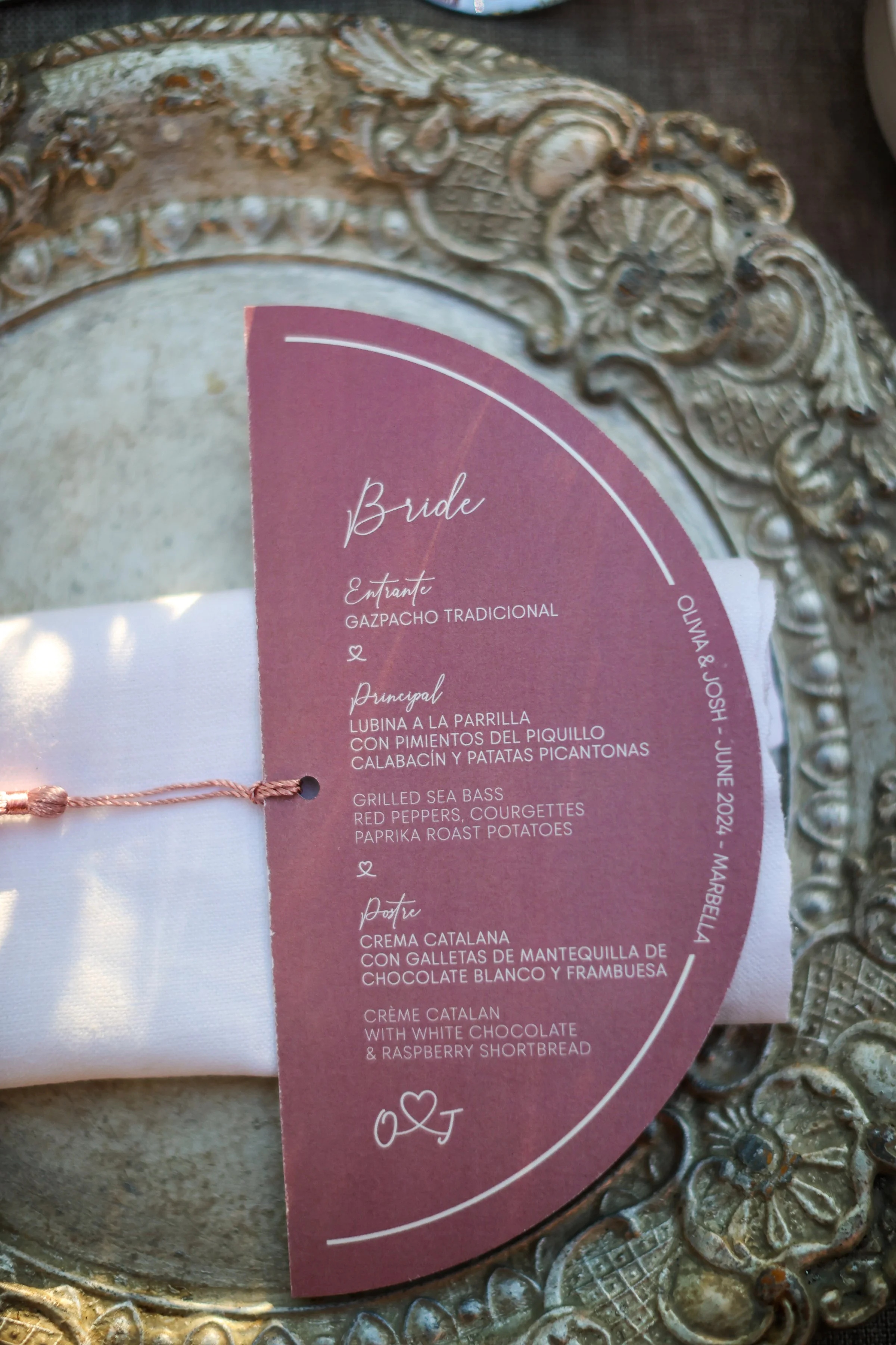 A decorative vintage mirror reflecting part of a pink menu card with Spanish and English text.
