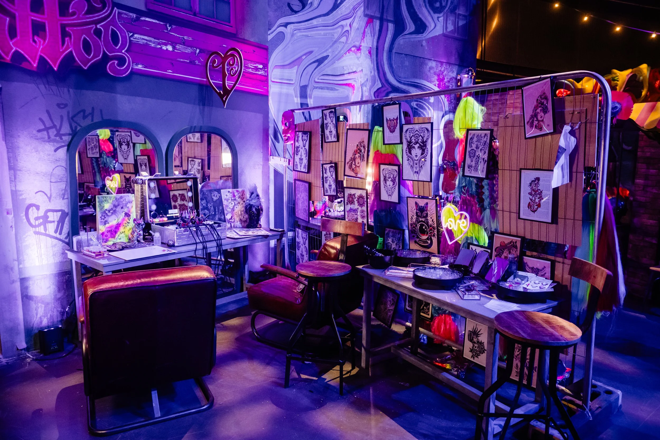 The Roundhouse venue decorated for a Bar Mitzvah with neon lights and artwork, featuring tables, chairs, and a display of tattoo designs on the walls.