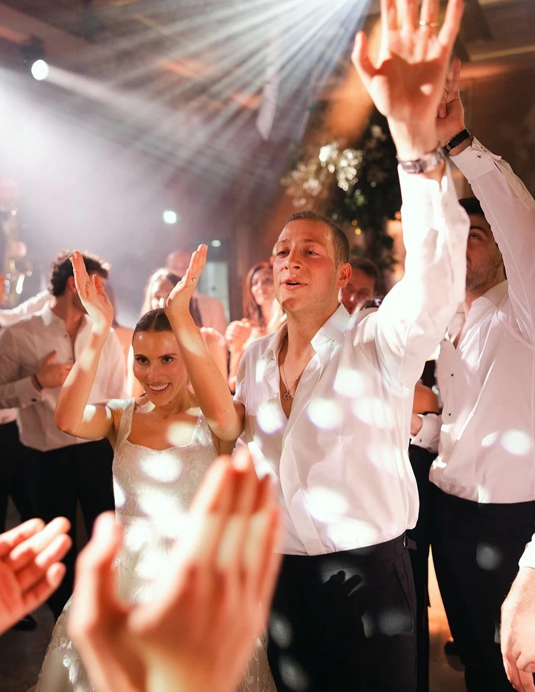 People dancing and celebrating at a wedding reception with joyful expressions and bright lights at The Peninsula London