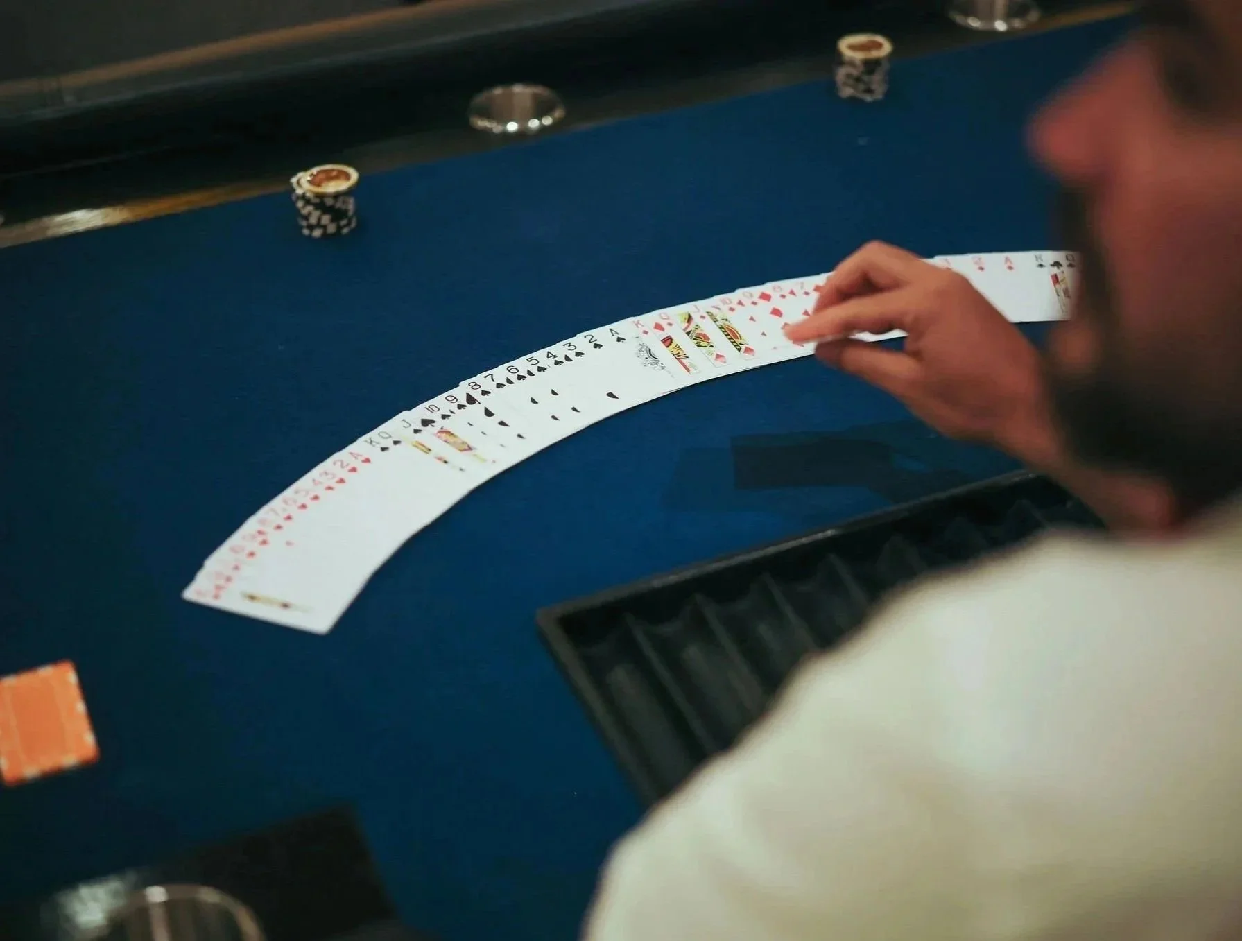 A person playing poker at a blue felt table, with a spread of playing cards and poker chips in front of them at Anantara Villa Padierna Resort in Marbella