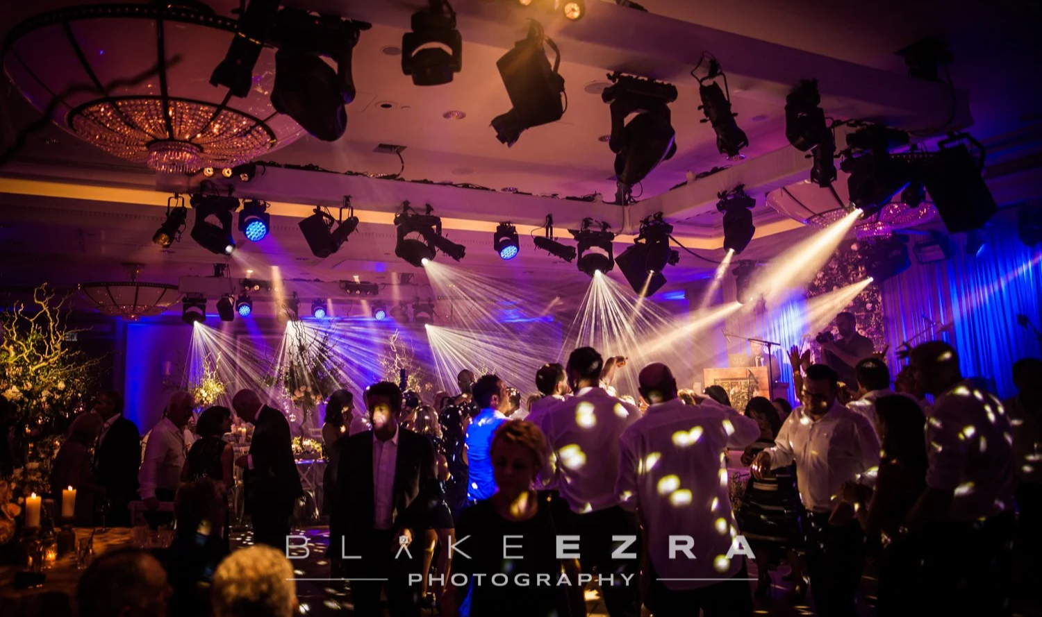 People dancing and socializing at an event with colorful lights and decorations in a large banquet hall at Rosewood London