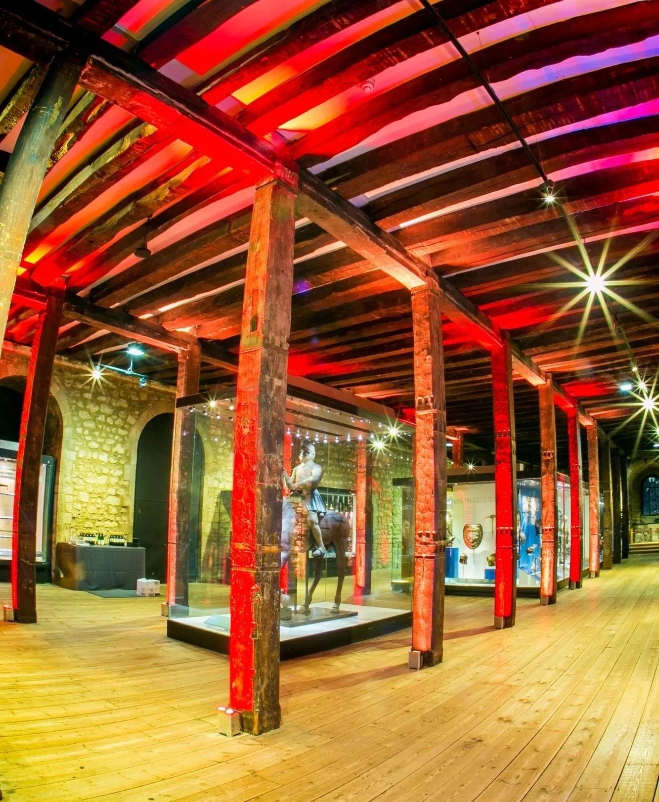 Interior of a museum with wooden beams and display cases containing artifacts at at the Tower of London