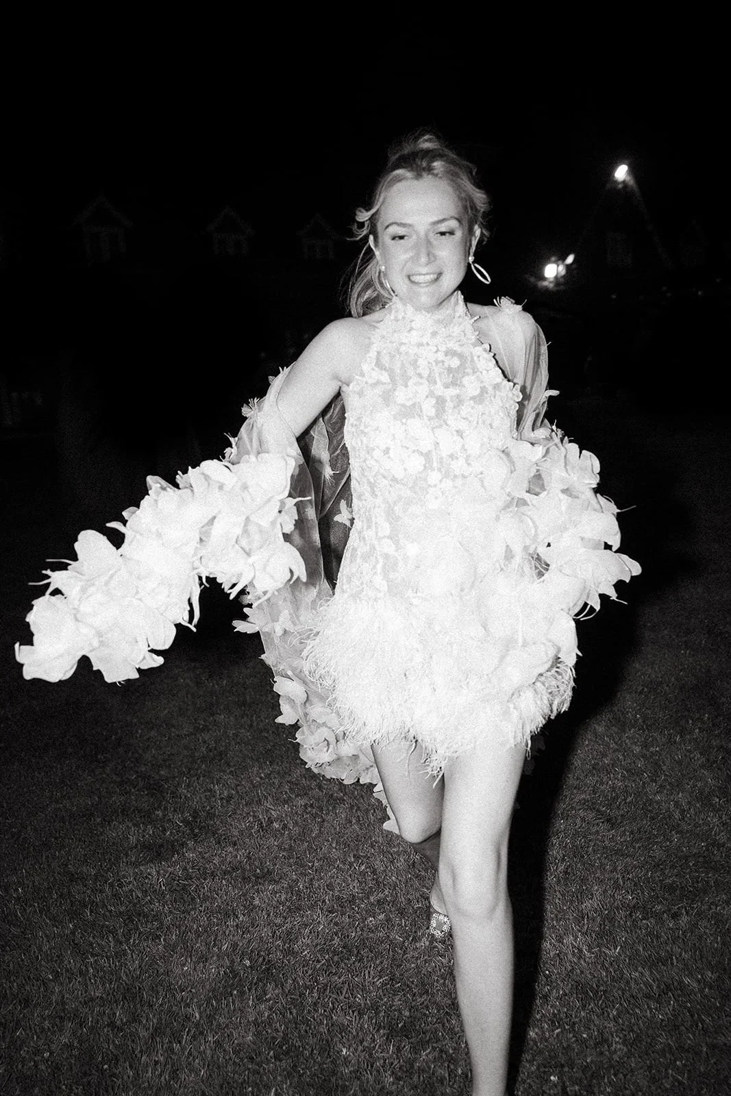 Private Residents Weddings and the bride has changed into her after party  floral dress with feathered hem running on grass to hidden club