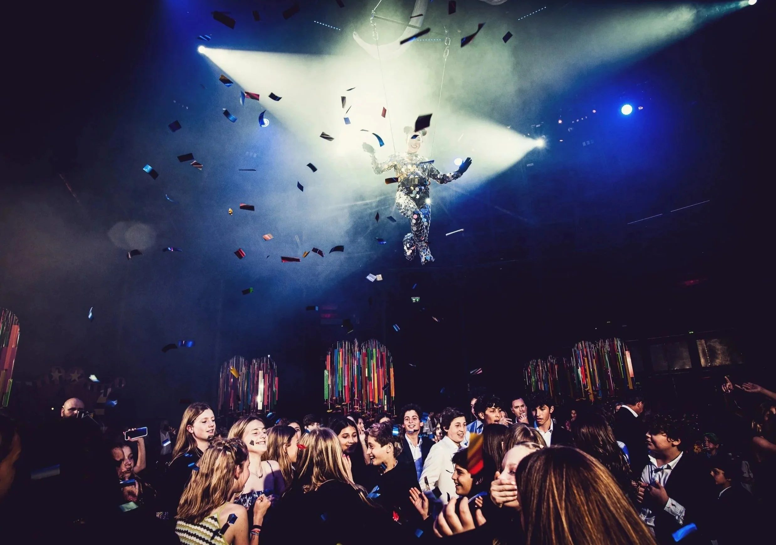  Bat Mizvah the roundhouse. young people at a party or celebration, with a performer or entertainer dressed in a shiny, reflective outfit and suspended from the ceiling.