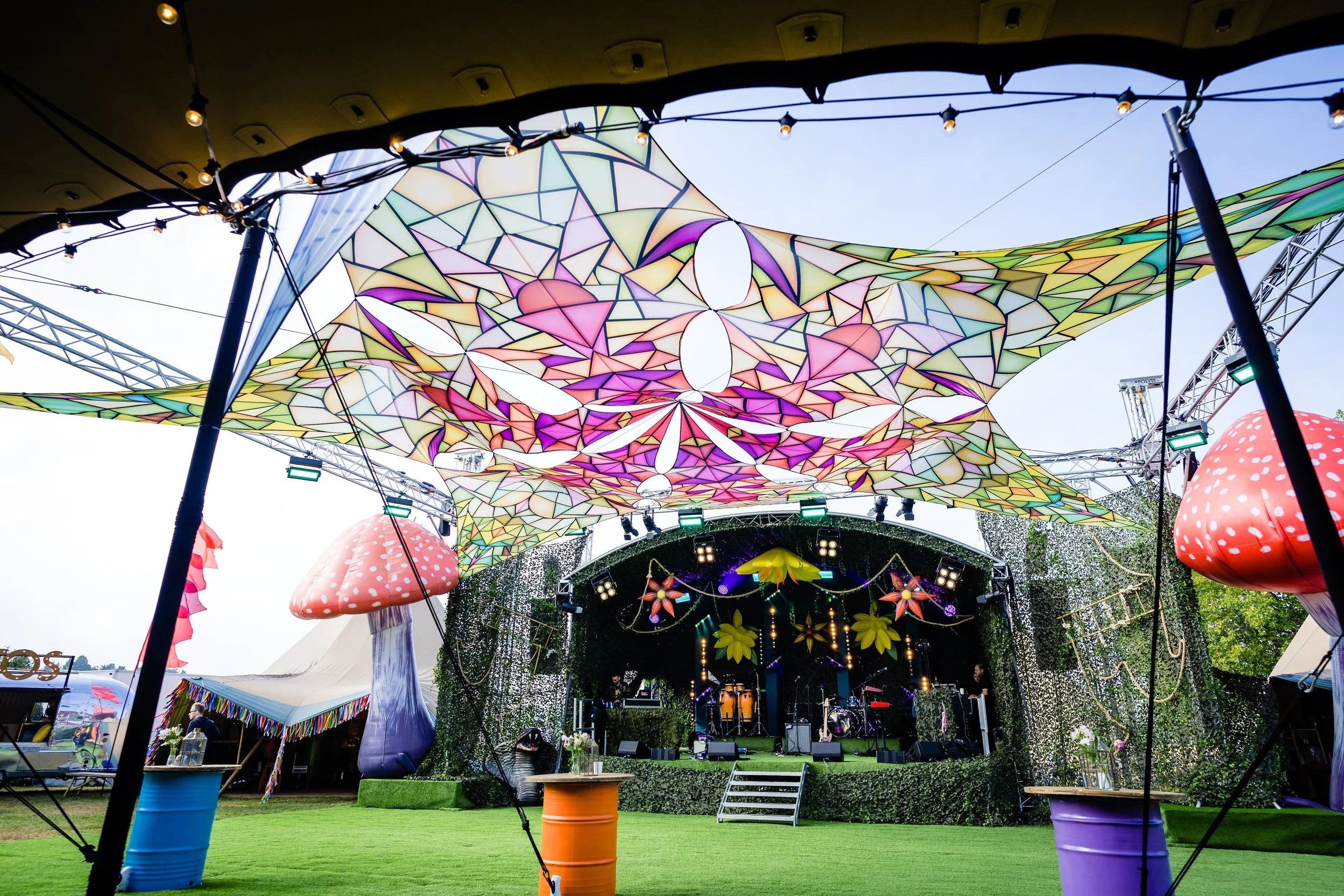 Colorful canopy for a festival themedBar Mitzvah at  Wrotham Park and stage decorations at an outdoor festival with mushrooms and lights 