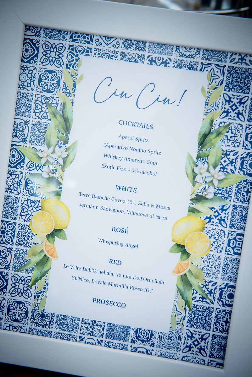 Table menu with cocktail and wine options surrounded by blue and white patterned border, decorated with lemon and citrus fruit illustrations.