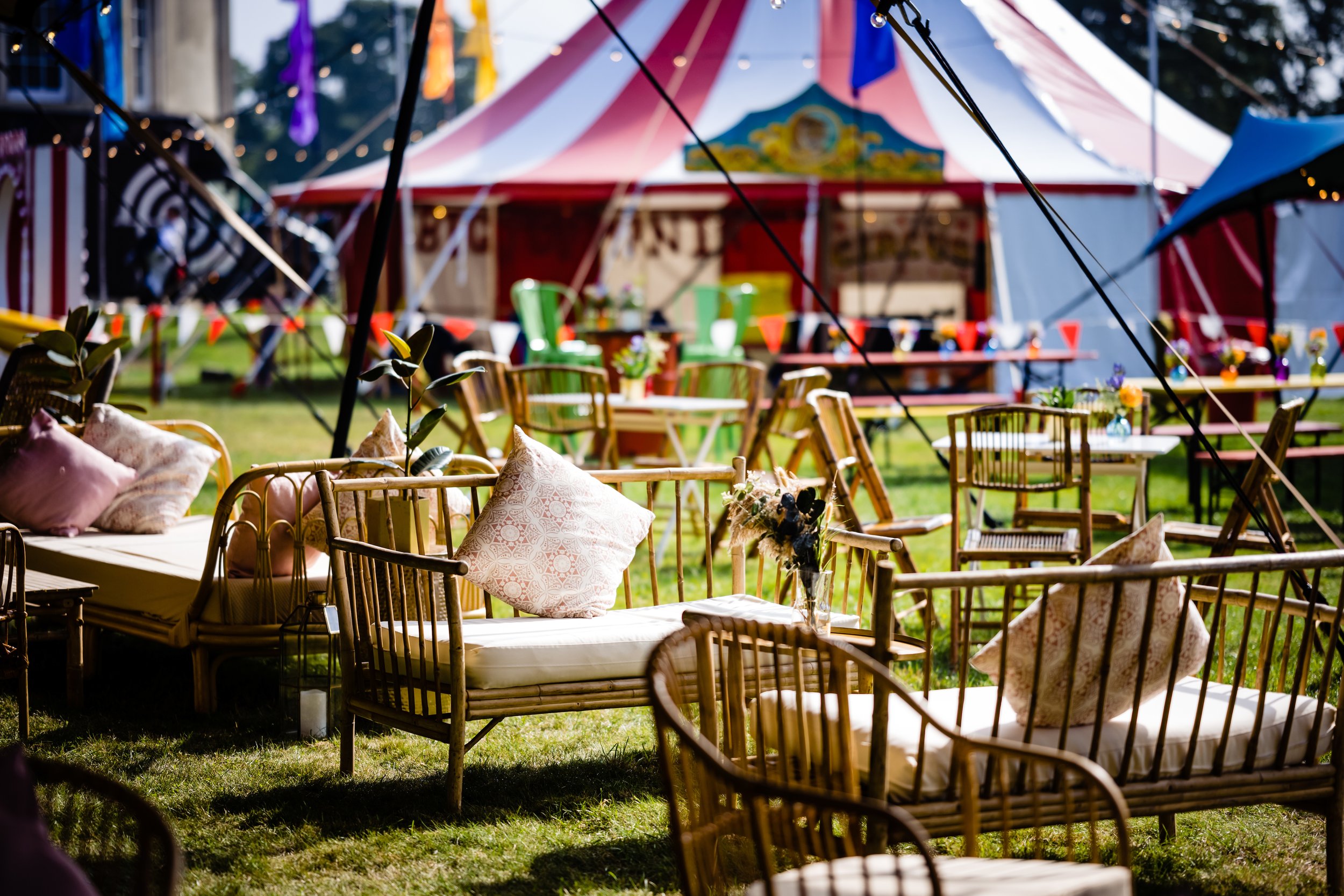 Outdoor carnival or fair setup with colorful tents, string lights, tables, chairs, and decorative pillows on a day with clear weather at a Bar Mitzvah at  Wrotham Park