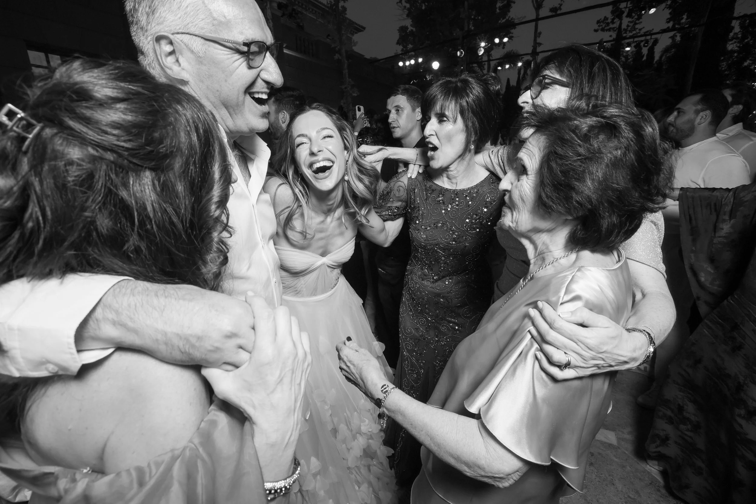 Group of people dancing and talking at a wedding after party at Anantara Villa Padierna Resort in Marbella, smiling, wearing formal and semi-formal attire.