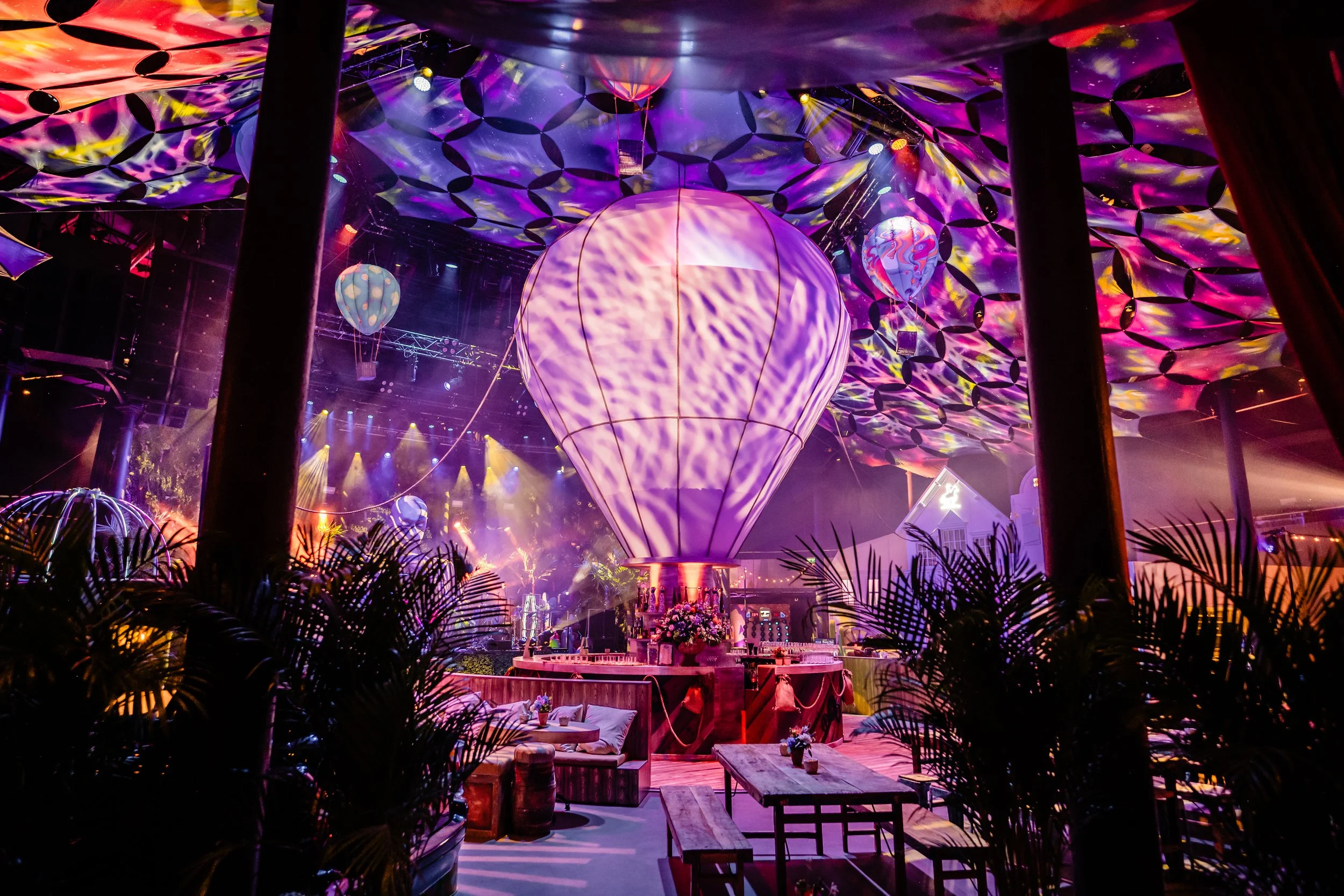 A vibrant Bar Mitzvah at The Roundhouse venue in london decorated with colorful lights and decor, featuring a large balloon-shaped centerpiece and hanging decorations, with seating and tables around.