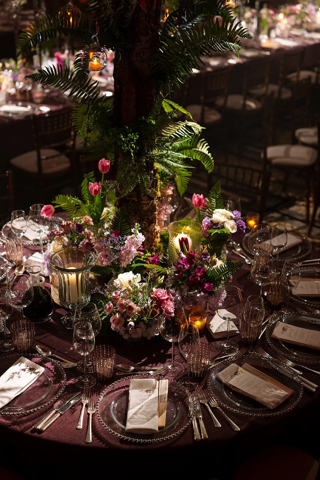 Elegant banquet table decorated with flowers, candles, and greenery, featuring pink, purple, and white blossoms, set for weding recpetion and dinner at The Peninsula London