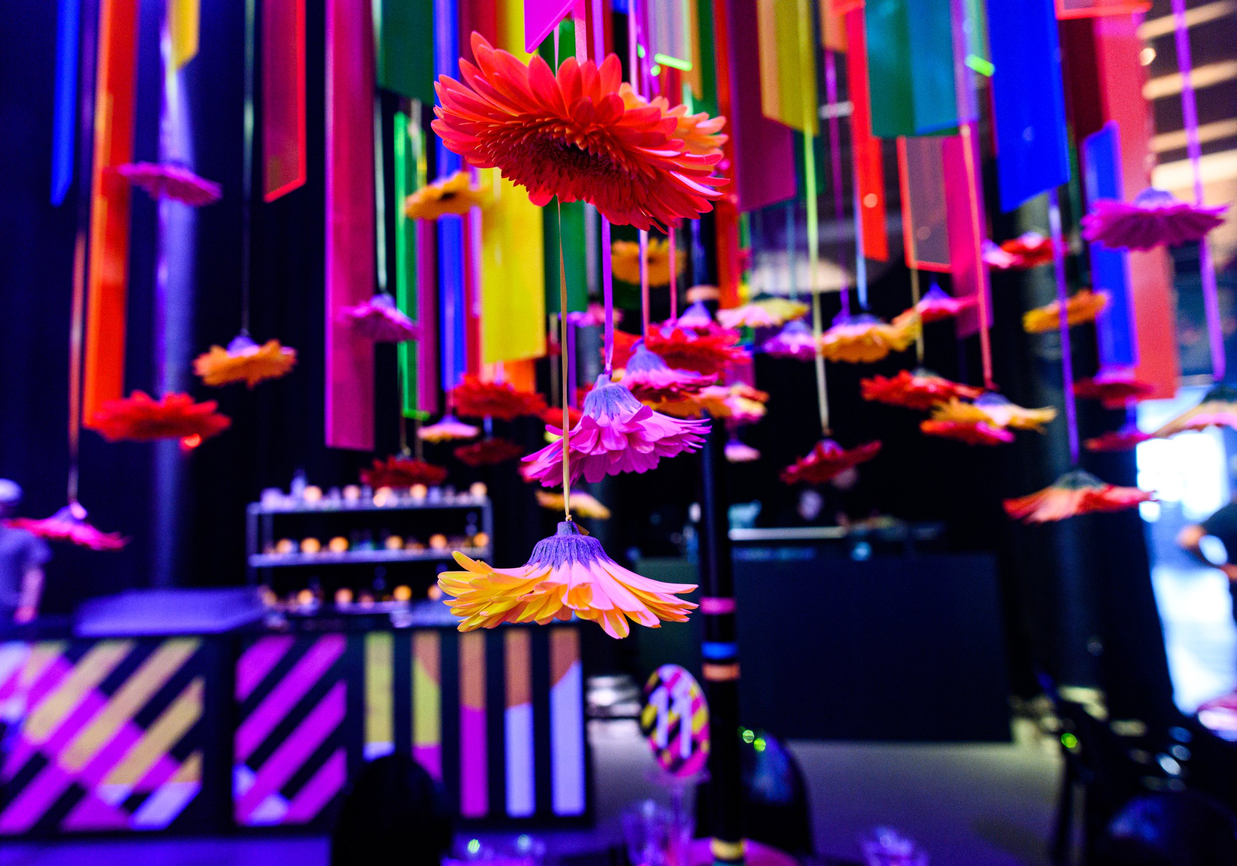 Colorful hanging paper flowers and rectangular paper strips in various bright colors in an artistic installation.  Bat Mizvah the roundhouse