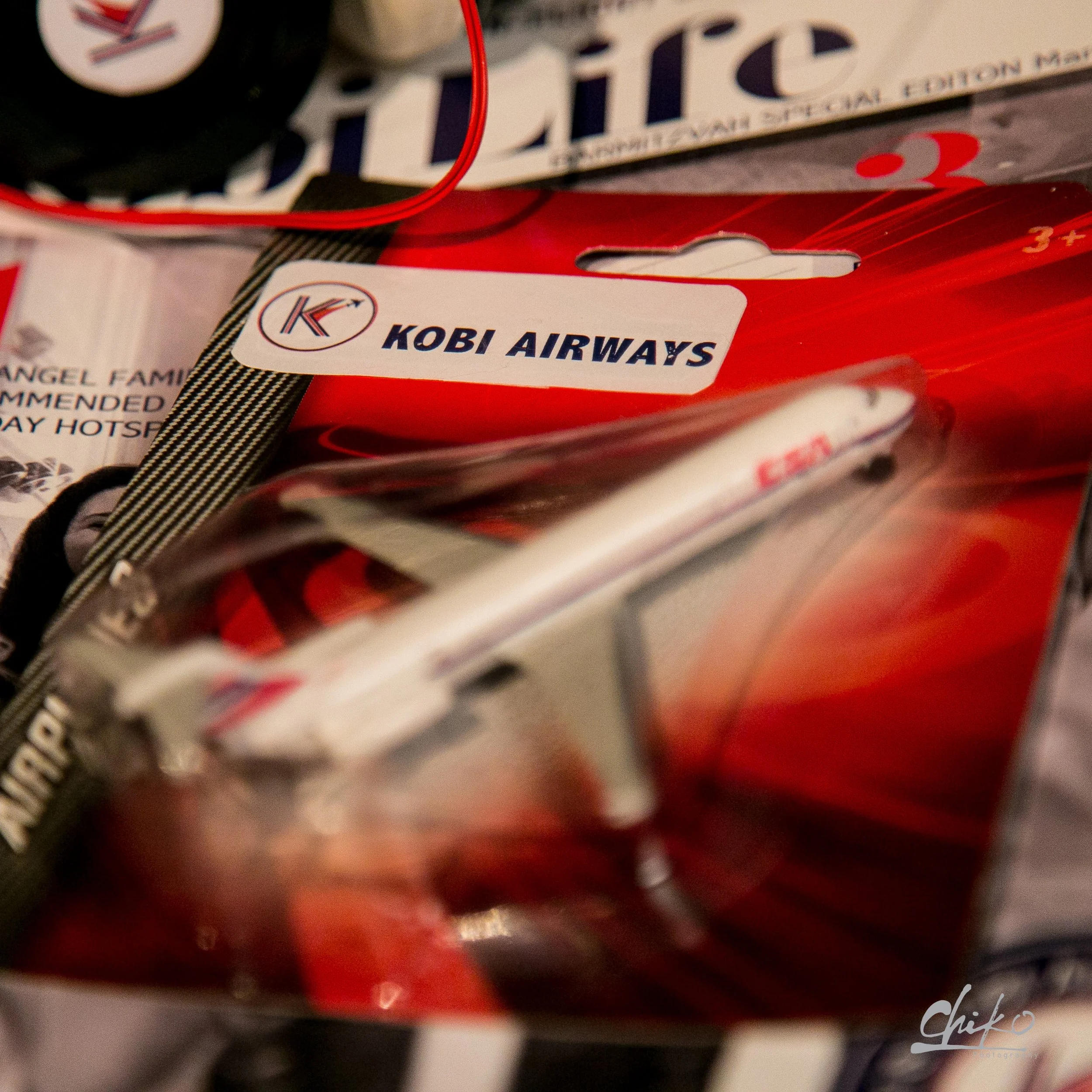 Close-up of a red packaging labeled 'Kobi Airways' with various other packages in the background.