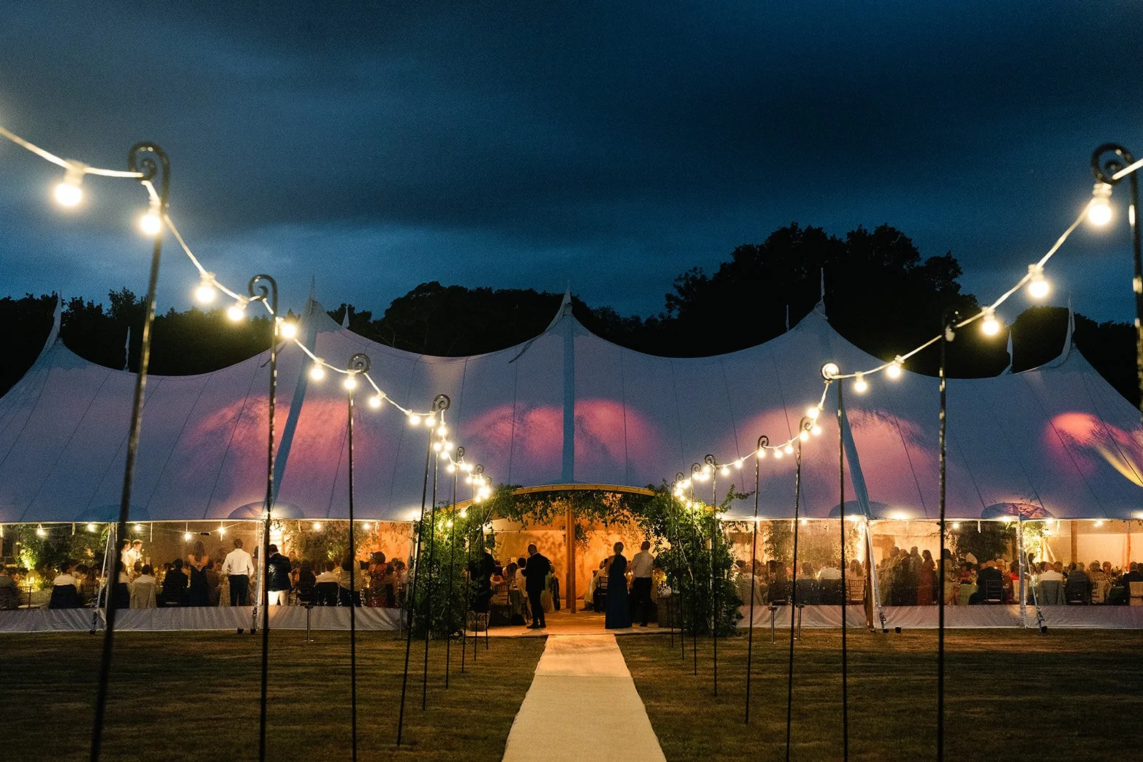 Nighttime outdoor wedding tent lit up with lights going to the door way