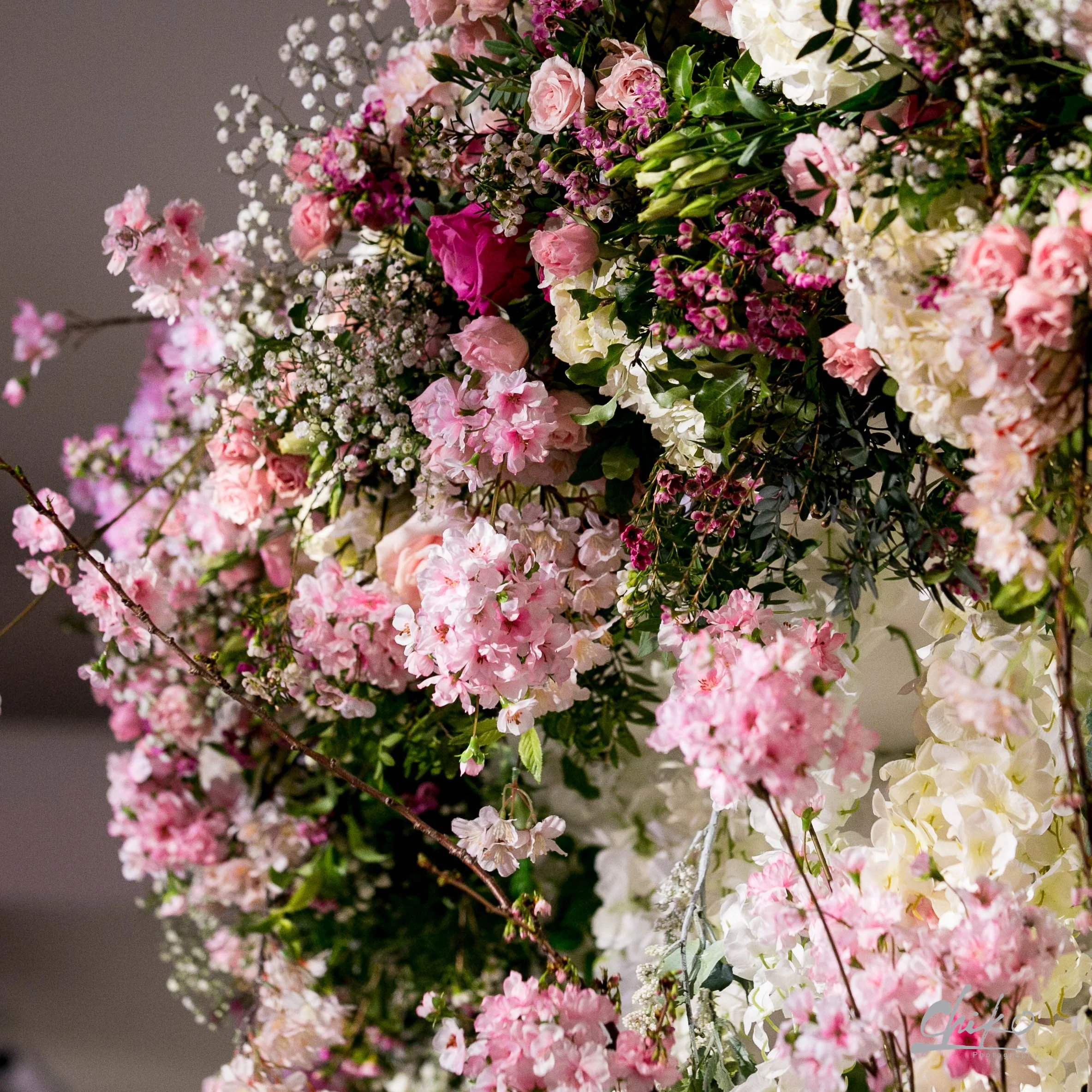 A large floral arrangement consisting of pink and white roses, small white filler flowers, and green foliage at Rosewood London
