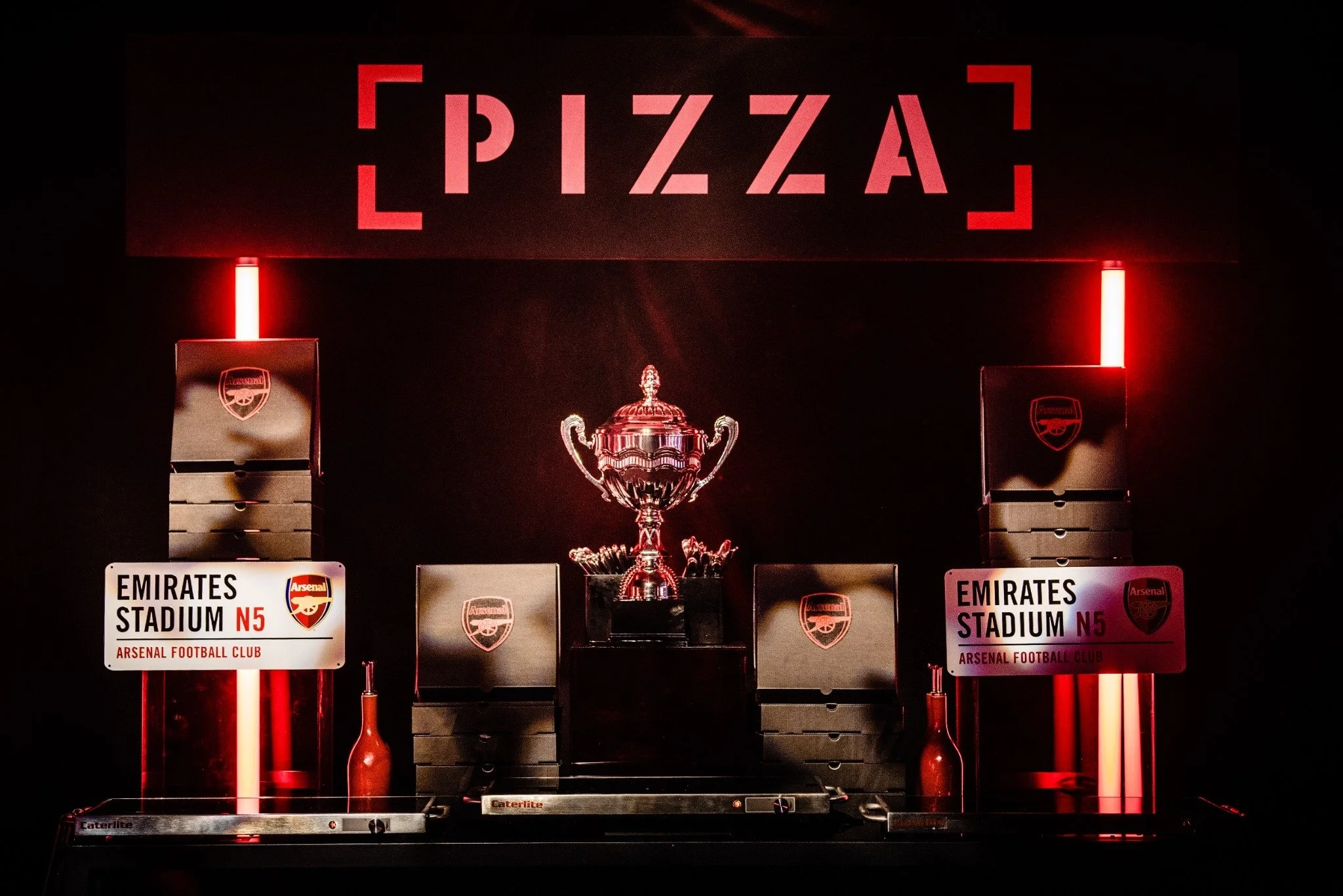 Display of a championship trophy and trophies at Emirates Stadium with signage for Arsenal Football Club, featuring red lighting and branding for N5.
