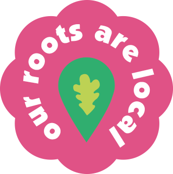 Pink flower-shaped badge with white text 'our roots are local' surrounding a green location pin with a yellow oak leaf inside.