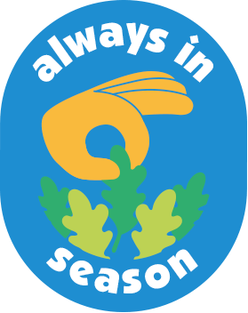 The image shows a logo with a blue circular background. Inside, there is a stylized yellow hand making an 'OK' gesture, with green leaves at the thumb and index finger. The words 'always in season' are written in white around the top and bottom of the circle.