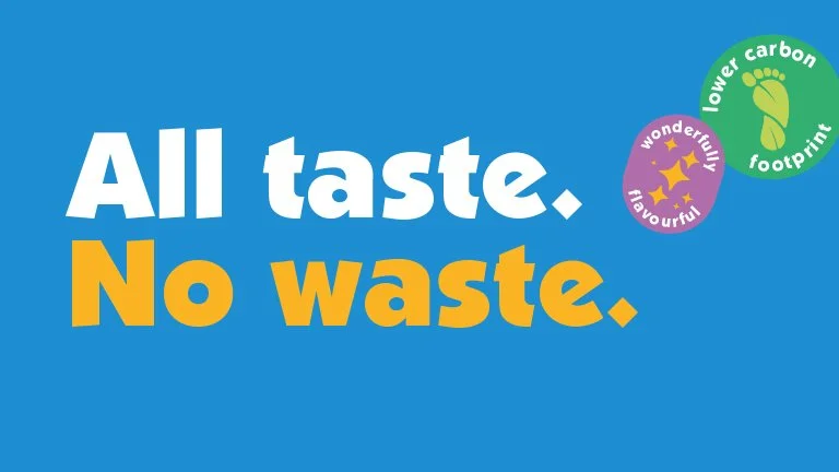 Text on blue background reading "All taste. No waste." with green and purple icons indicating "lower carbon footprint" and "wonderfully flavorful."