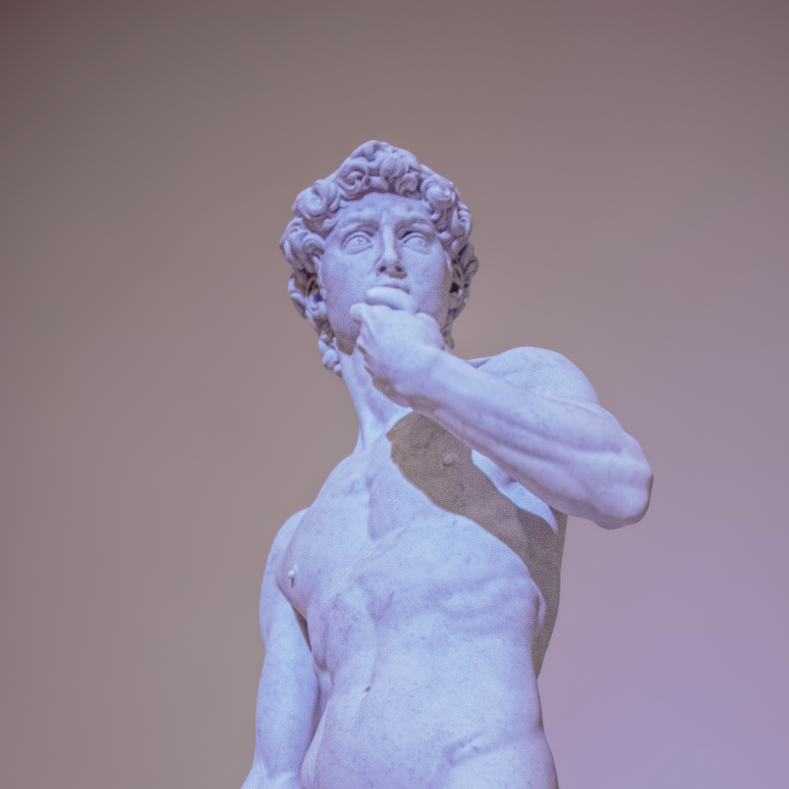 Marble sculpture of a thinking man with curly hair, resting his chin on his hand, against a plain background.