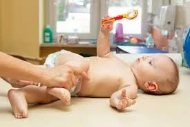 A baby lying on a changing table, receiving a diaper change from an adult.
