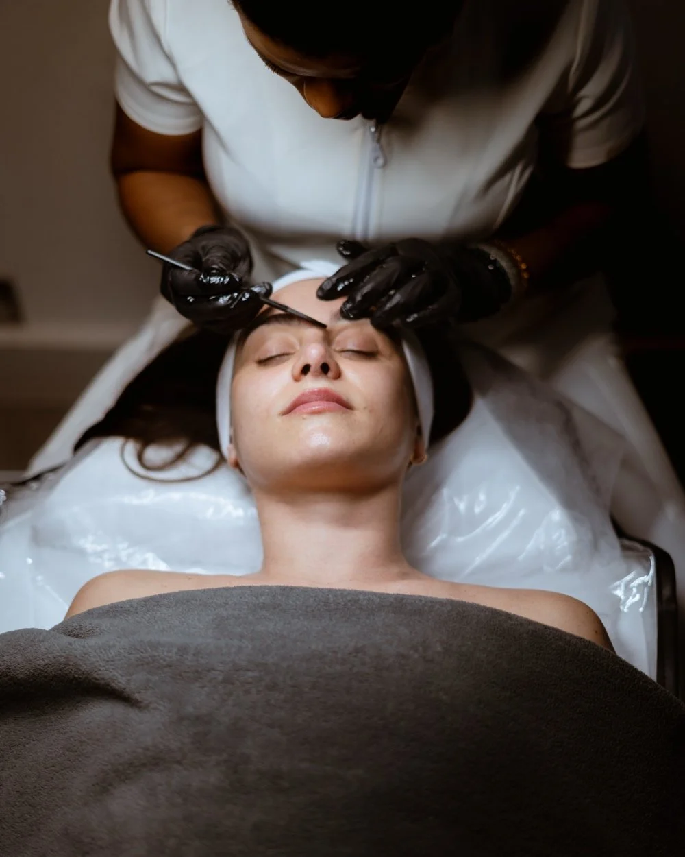 A woman getting a cosmetic facial procedure done, lying down with eyes closed