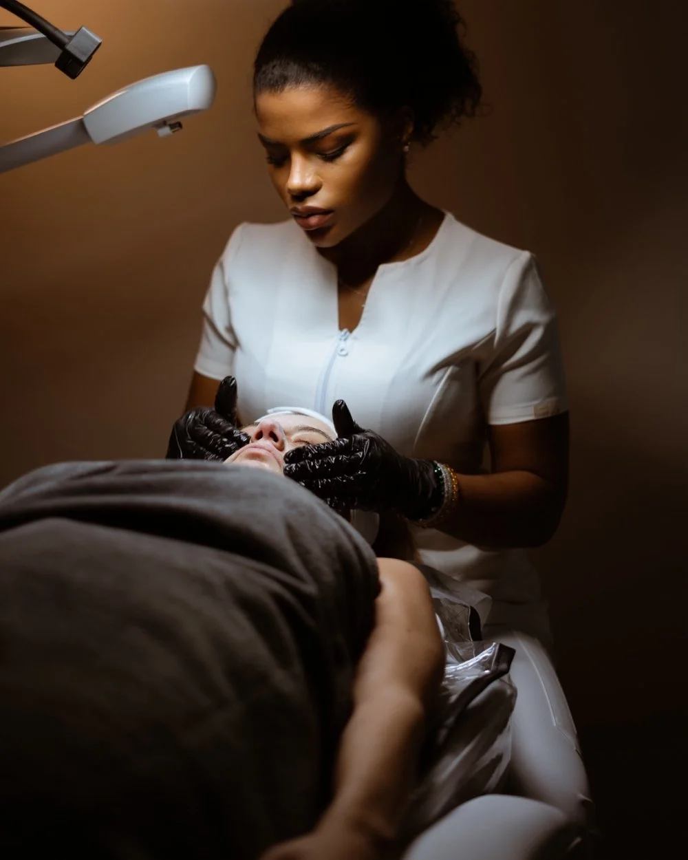 Aesthetic photo of a woman in a white uniform performing a skincare treatment