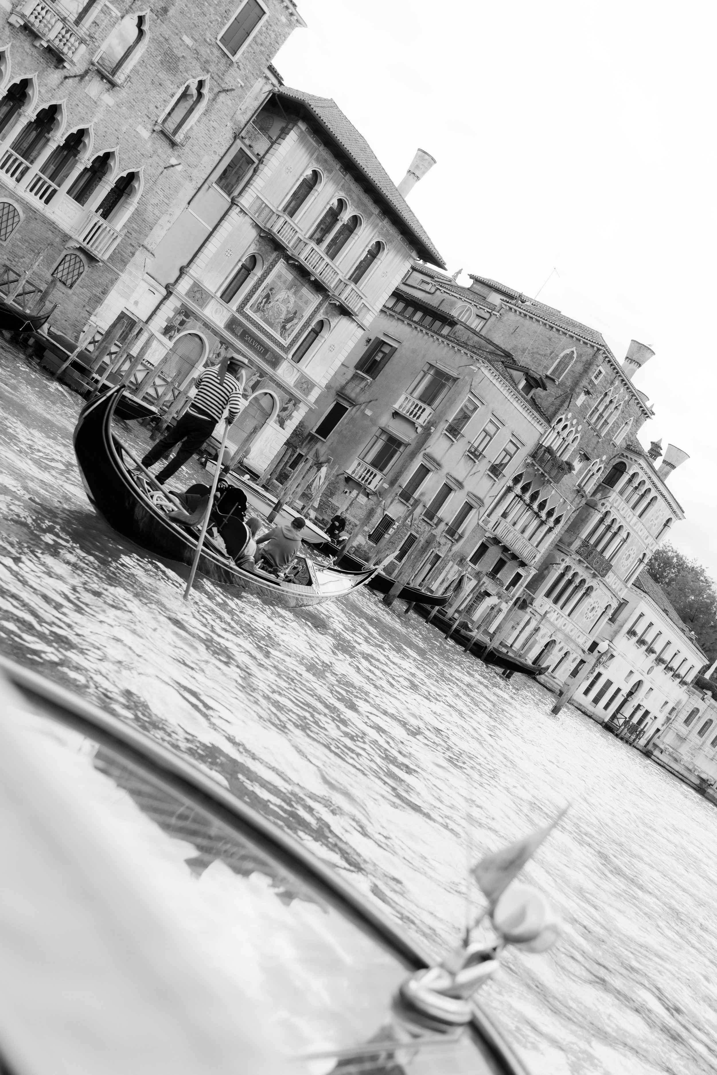 Gondola on a Venetian canal with historic buildings in black and white.