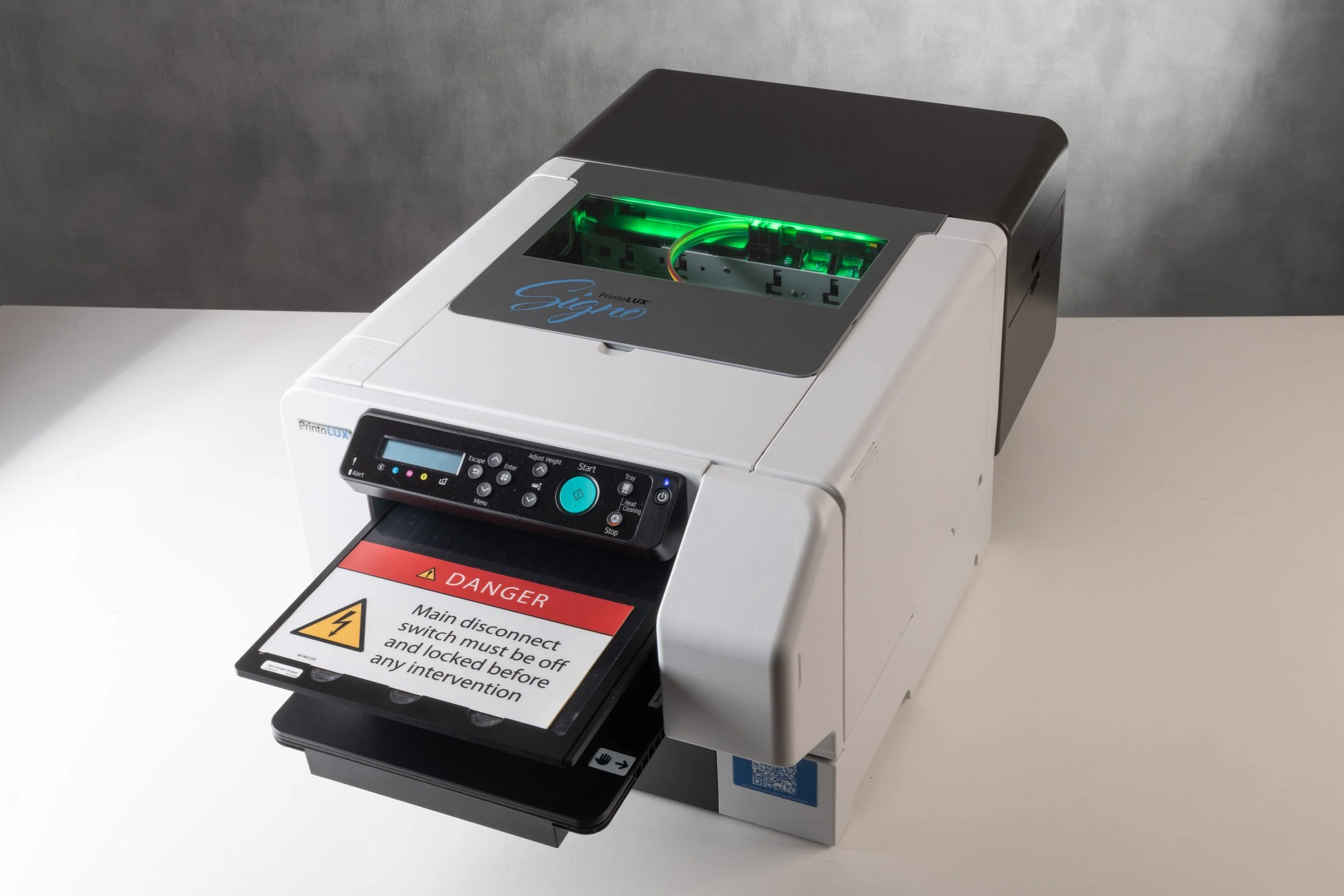 The Printolux Signo machine with a warning label that reads, ‘Danger: Main disconnect switch must be off and locked before any intervention.' after printing.