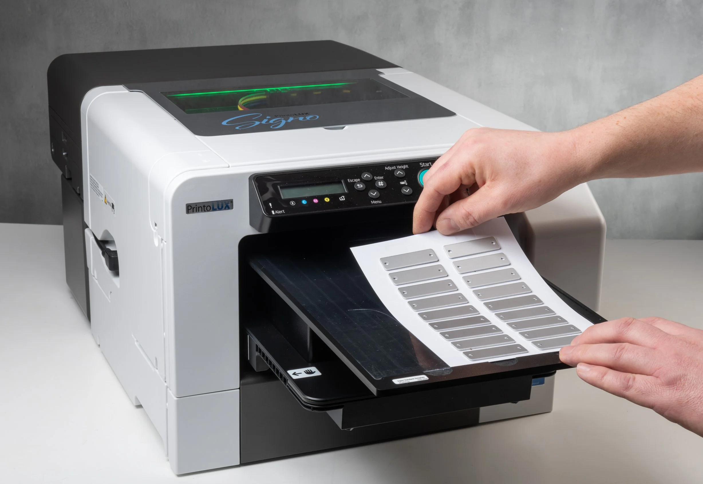A person is inserting a sheet of small metal cable tags into the Printolux Signo machine.