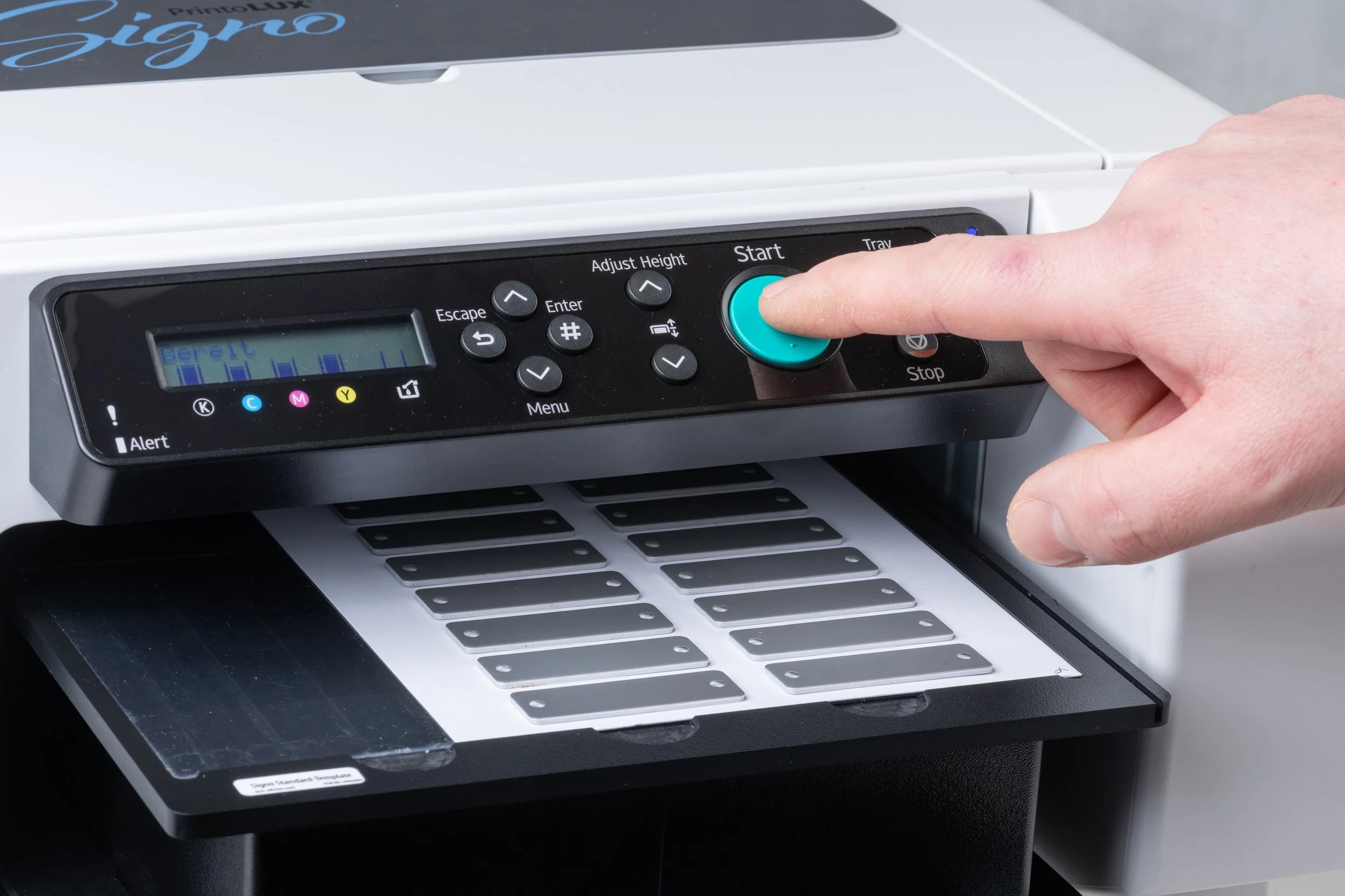A person pressing the start button on the Printolux Signo.