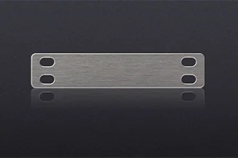 A metal cable tag with four holes, two on each side, on a dark background.