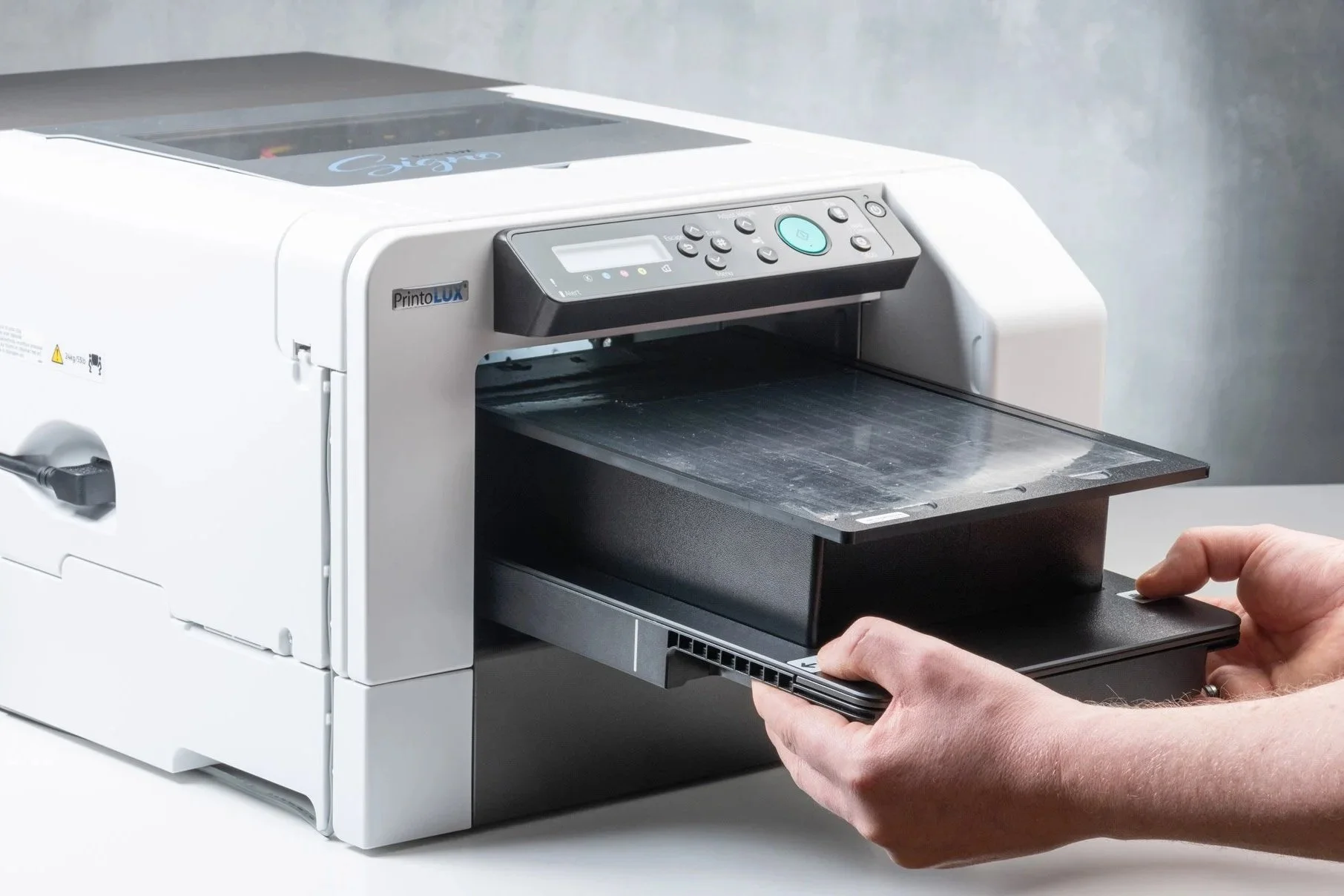 A person operating a Signo PrintoLUX industrial printer, preparing the print bed.