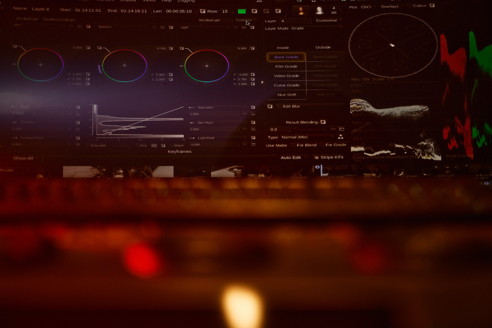 A computer screen shows video editing software with color adjustment controls, graphs, and a waveform display.