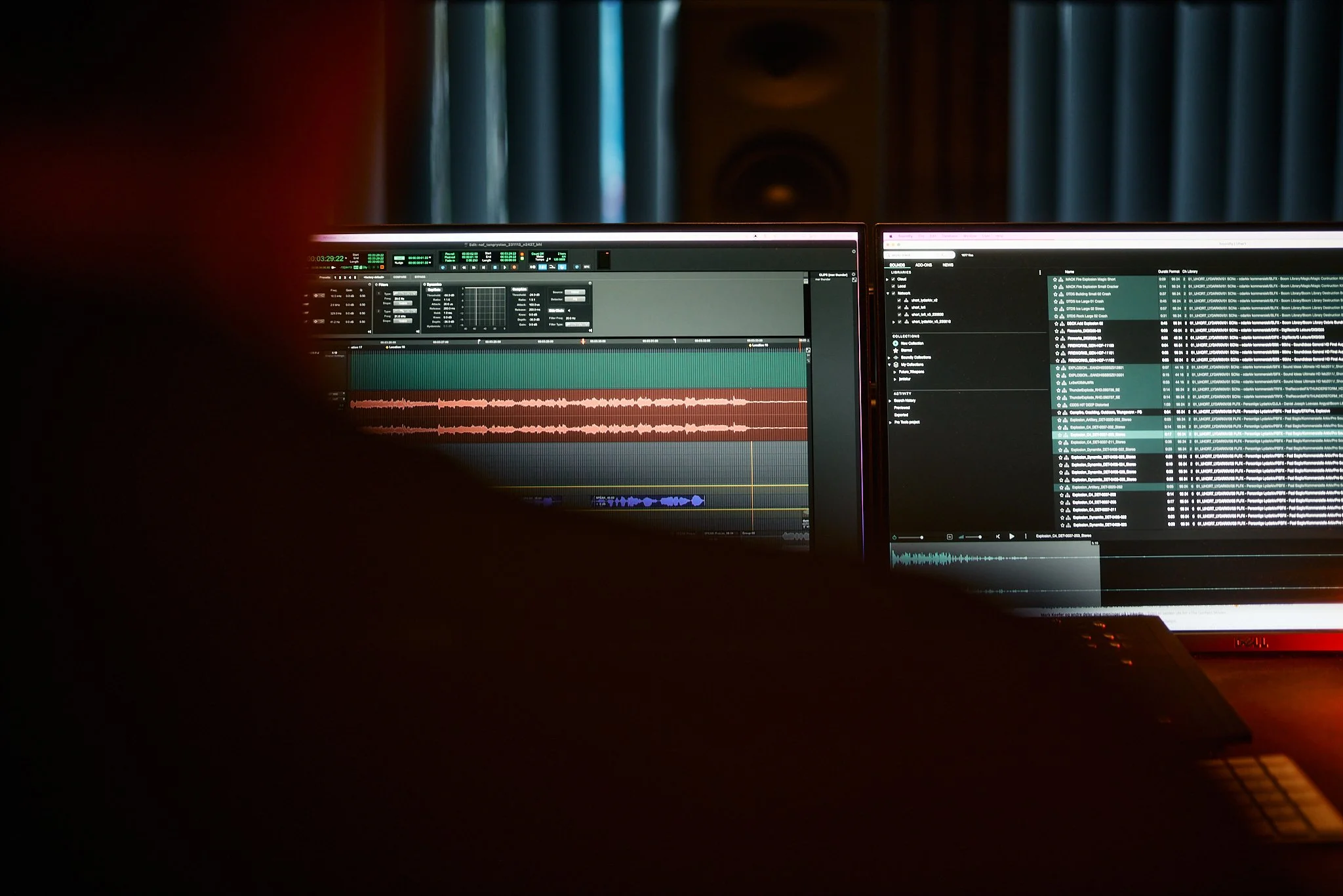 Two computer monitors displaying audio editing software and music files in a dimly lit room.