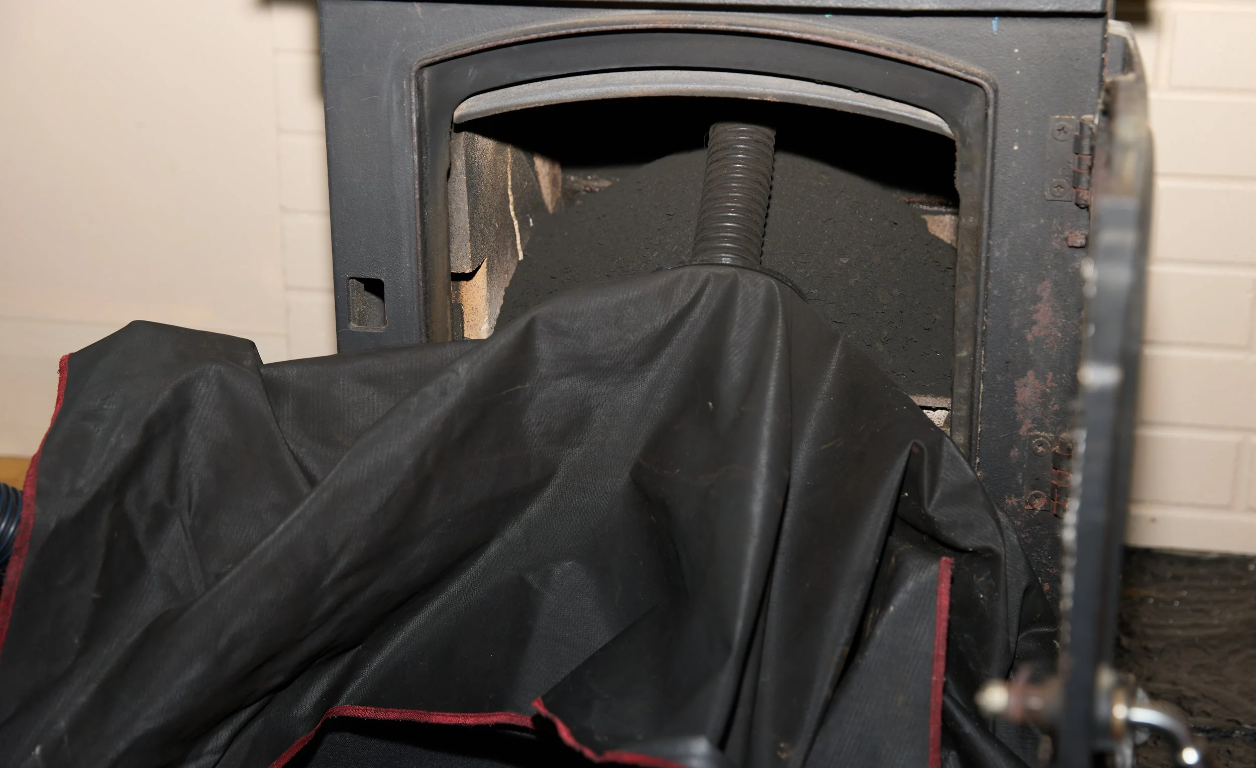 Inside a wood stove with a black stove pipe, black soot, and a black cover or bag.