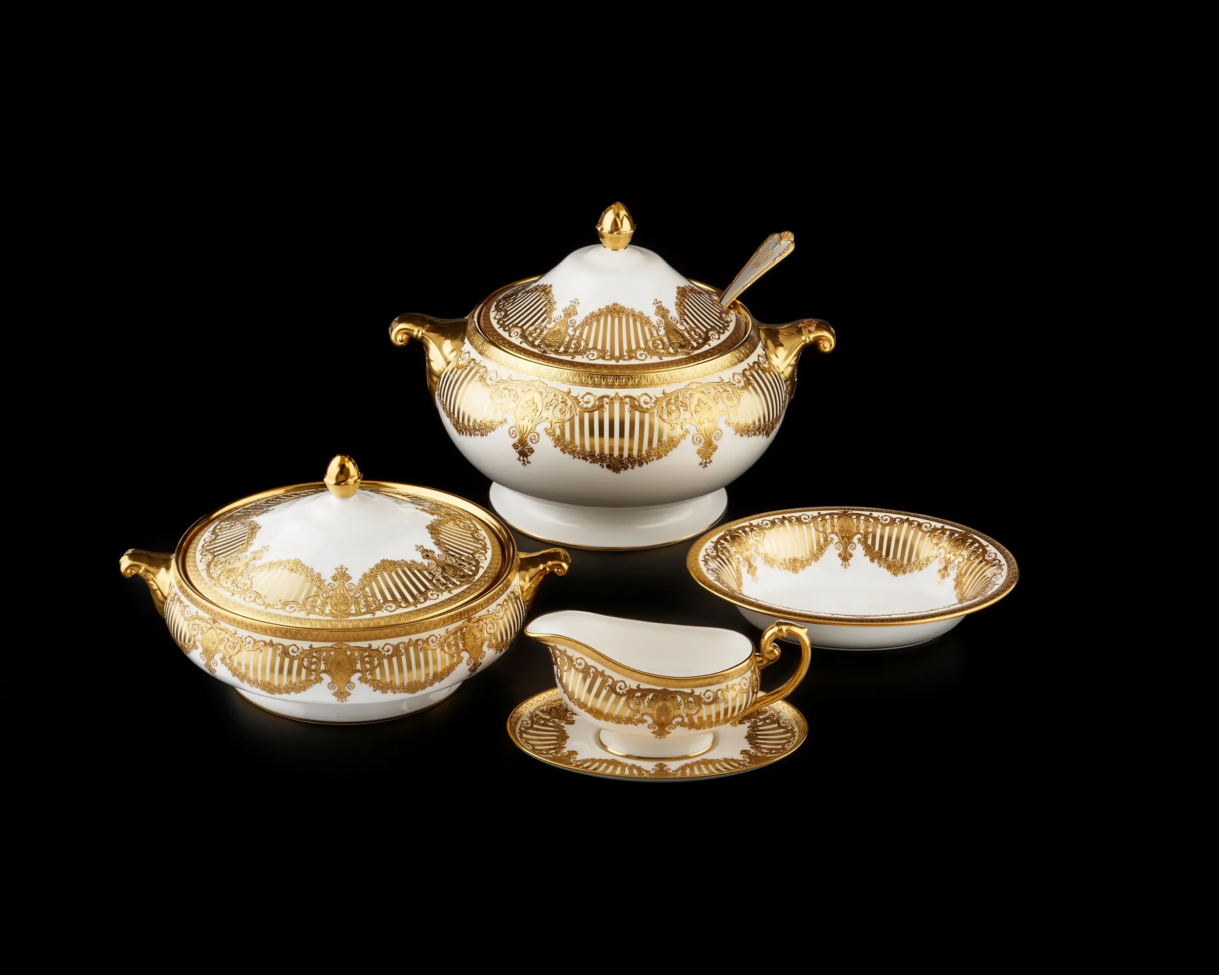 Porcelain tea set with gold accents and intricate designs on a black background.