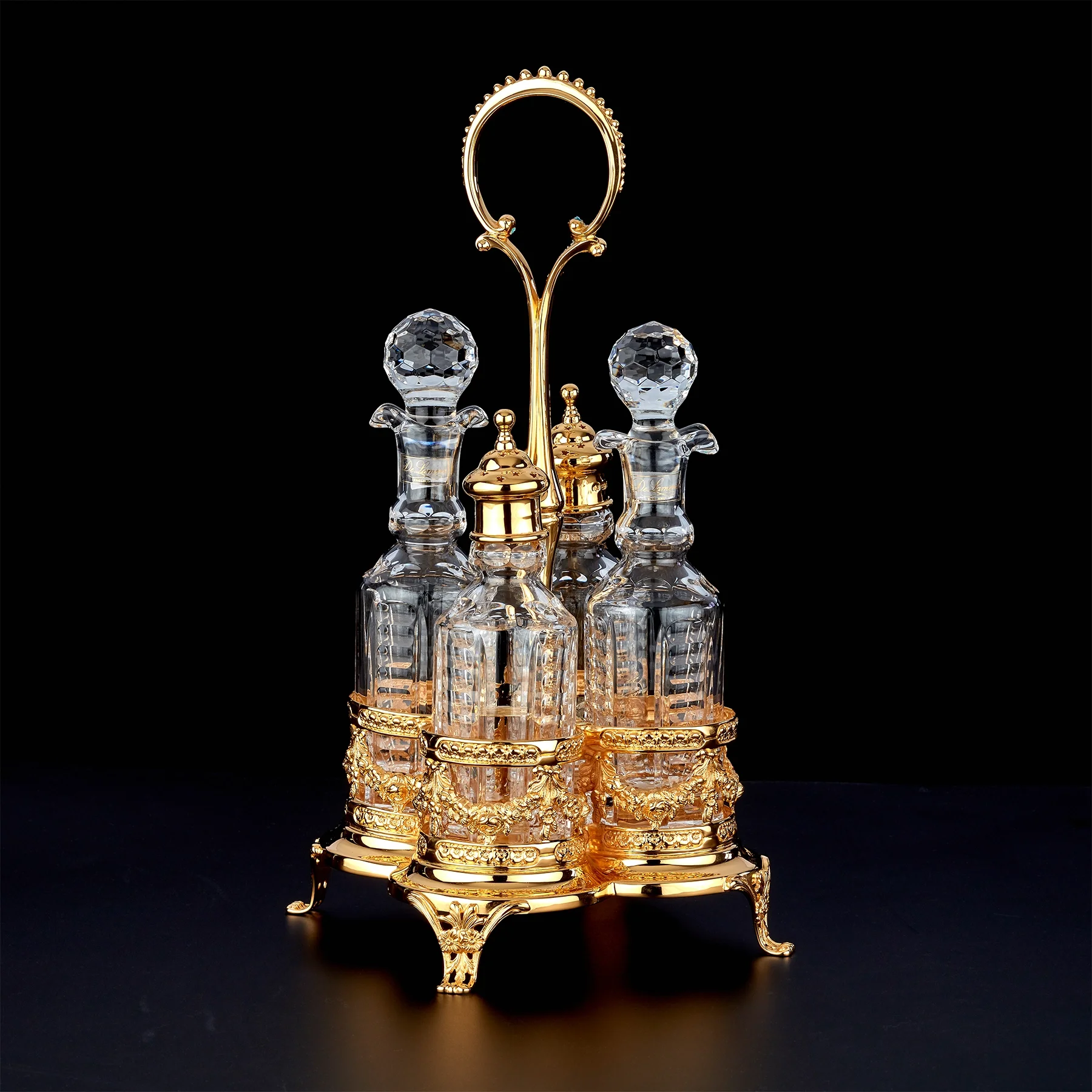 Ornate gold jewelry stand with crystal bottles and decorative gold accents, holding a gold ring with a beaded edge.