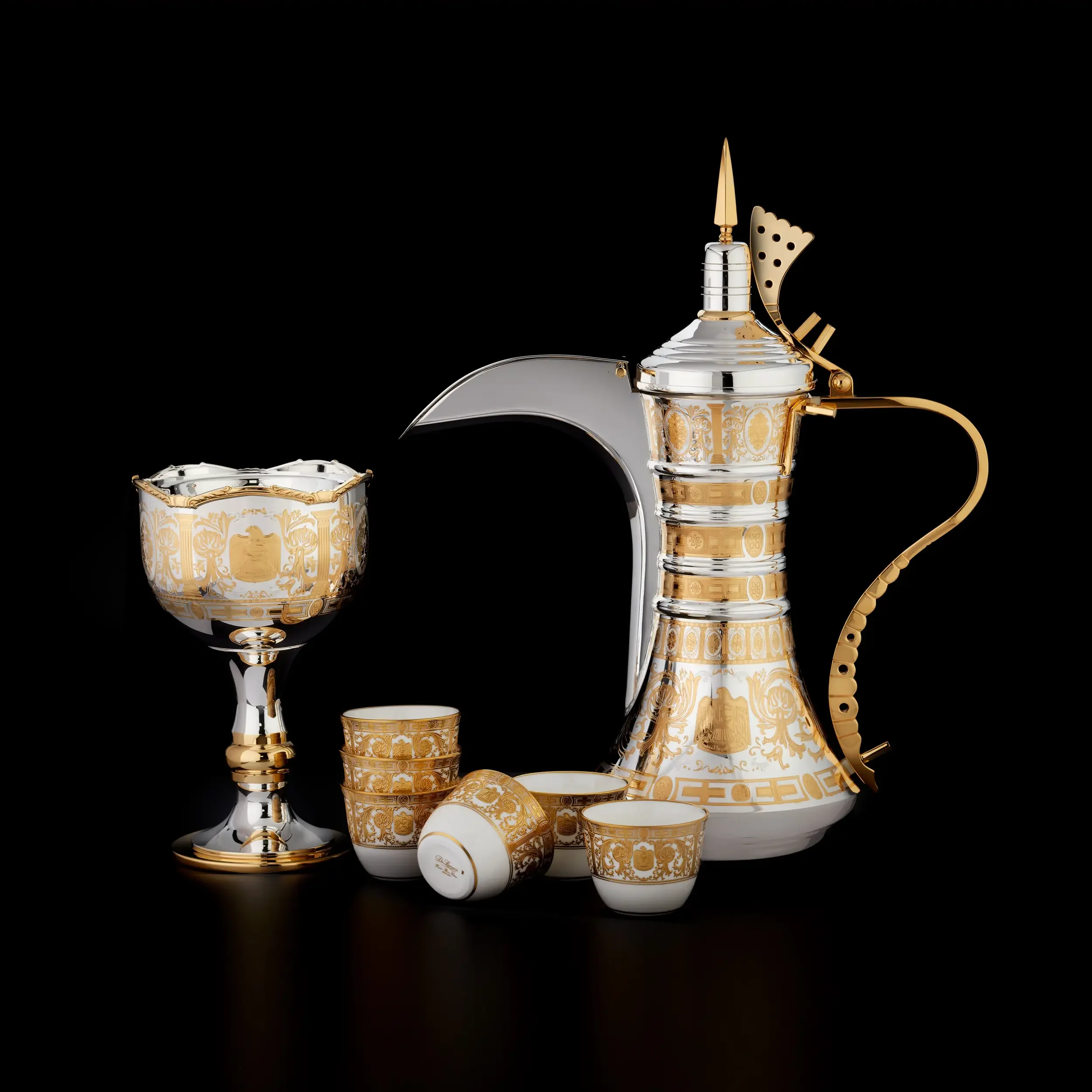 Decorative silver and gold ceremonial items on a black background, including a chalice, a goblet, a tray, and a cone-shaped object, all ornate with intricate patterns.