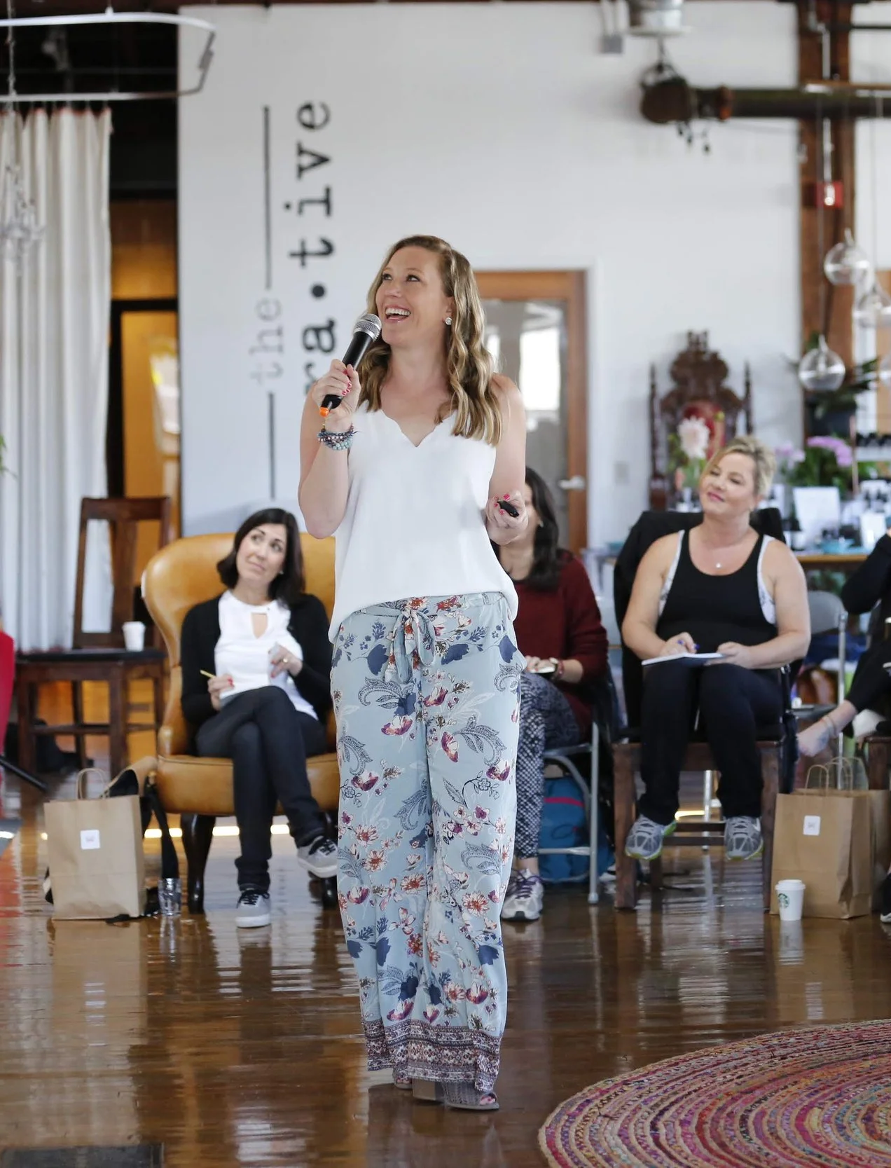 Mary Allison Jensen, LICSW, speaking on stage with a microphone to an engaged audience — available for speaking engagements on self-abandonment, generational healing, and conscious self-leadership.