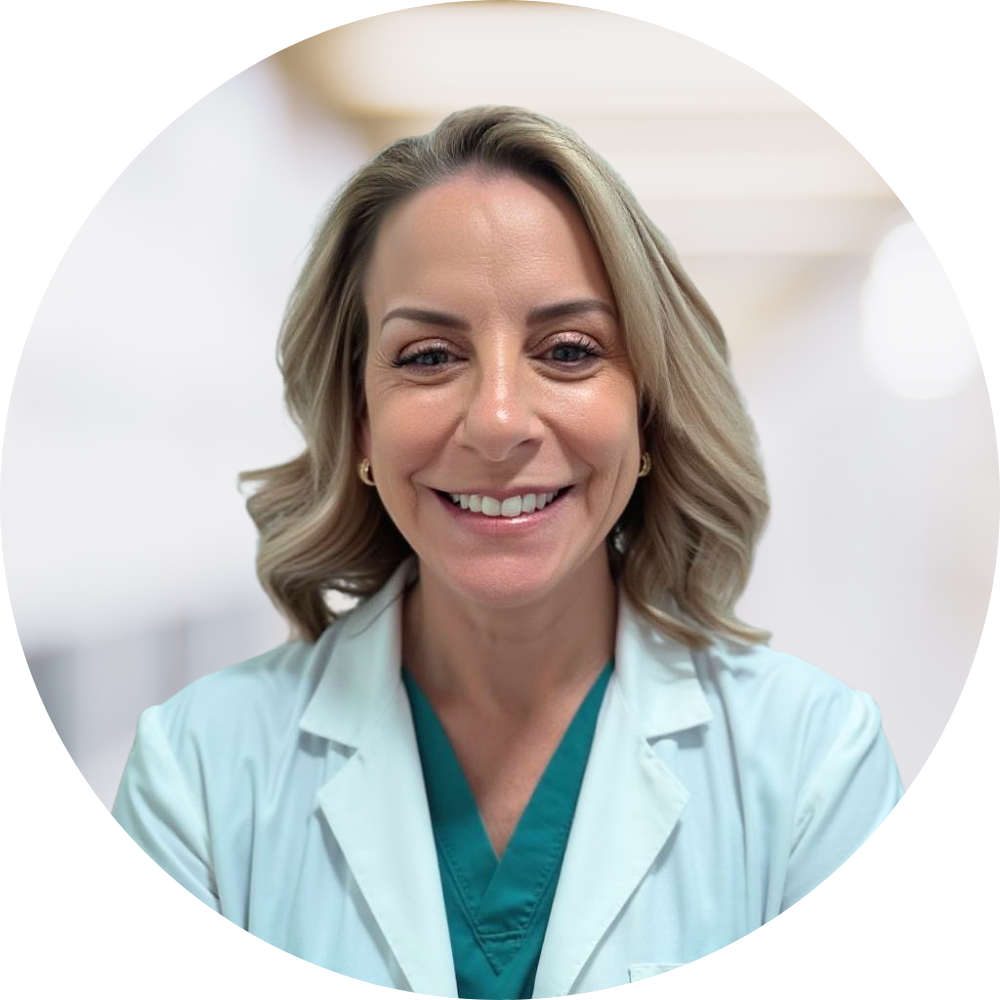 Smiling female doctor with blonde hair in medical coat and green scrubs.