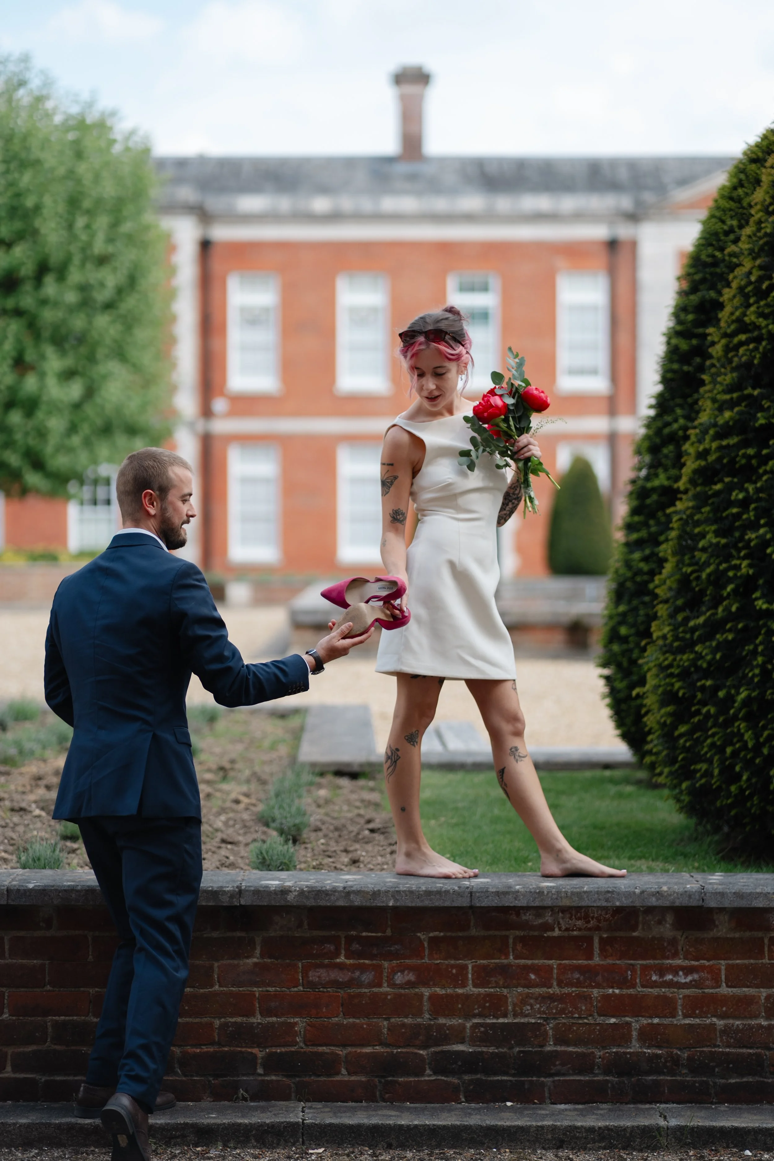 bride-removing-heels-garden-wall-candid.jpg
