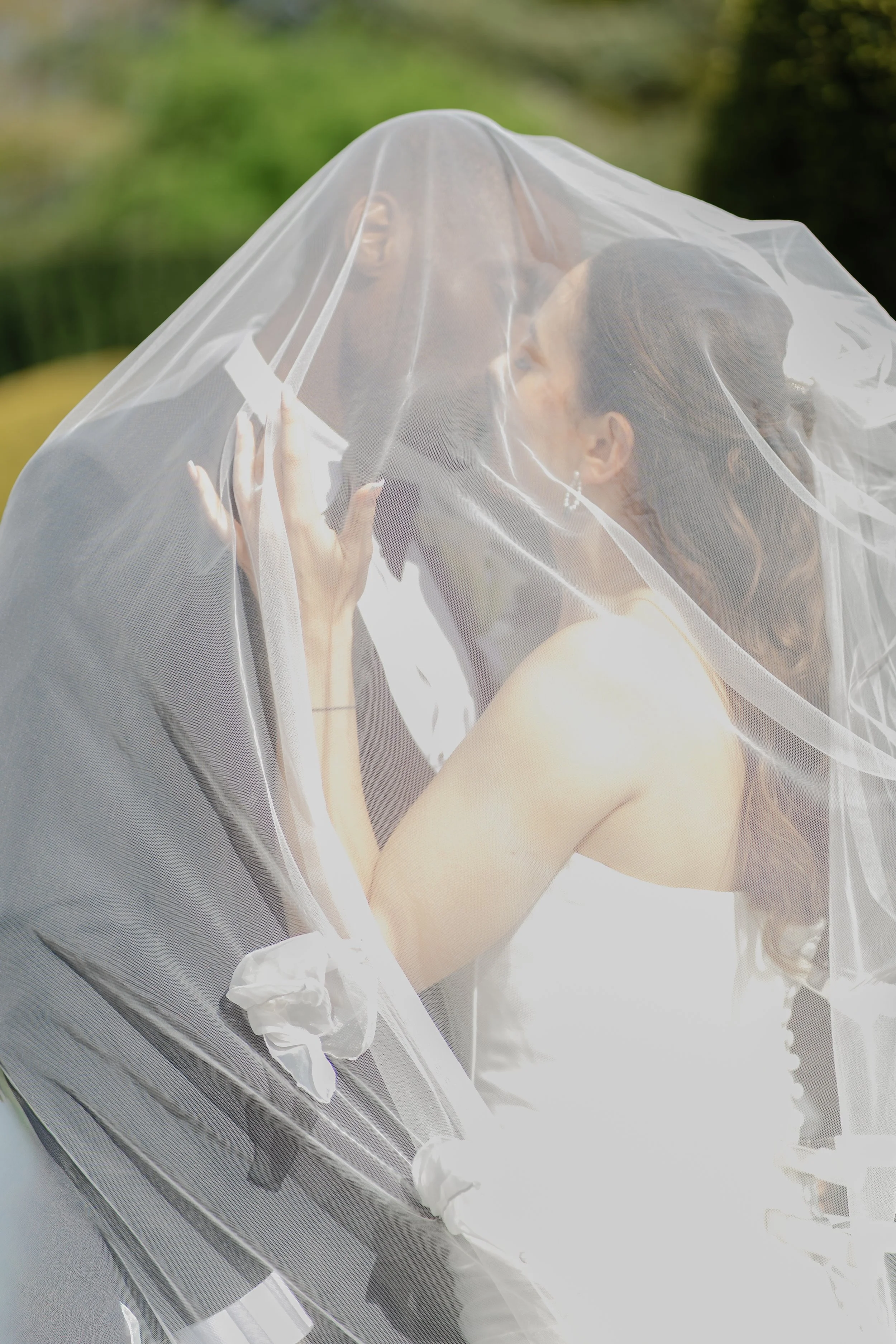 bride and groom under a veil sharing a kiss at their wedding